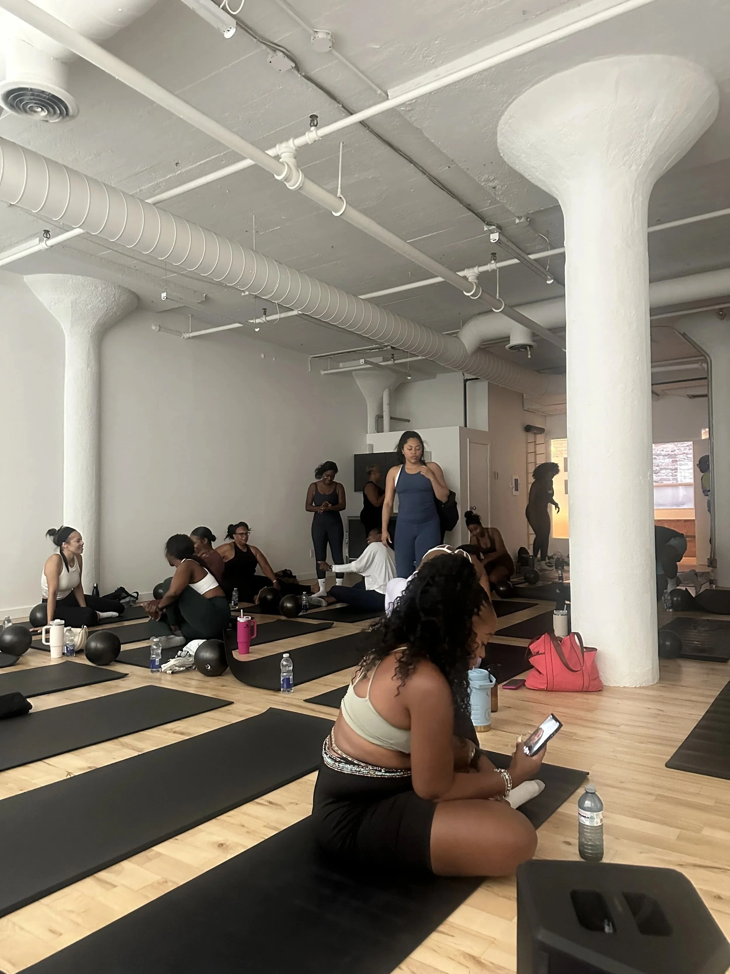 Guests seated on yoga mats during an R&B-inspired pilates class at Mood + Movement by That Slow Jam Party.