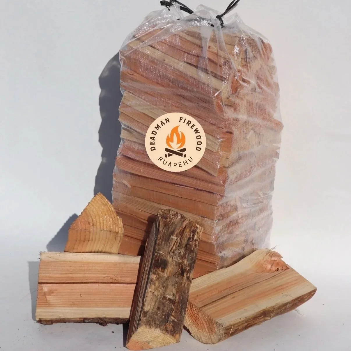 A large bag of wooden firewood pieces labeled 'Deadman Firewood Ruahehu,' with some wood pieces arranged in front.
