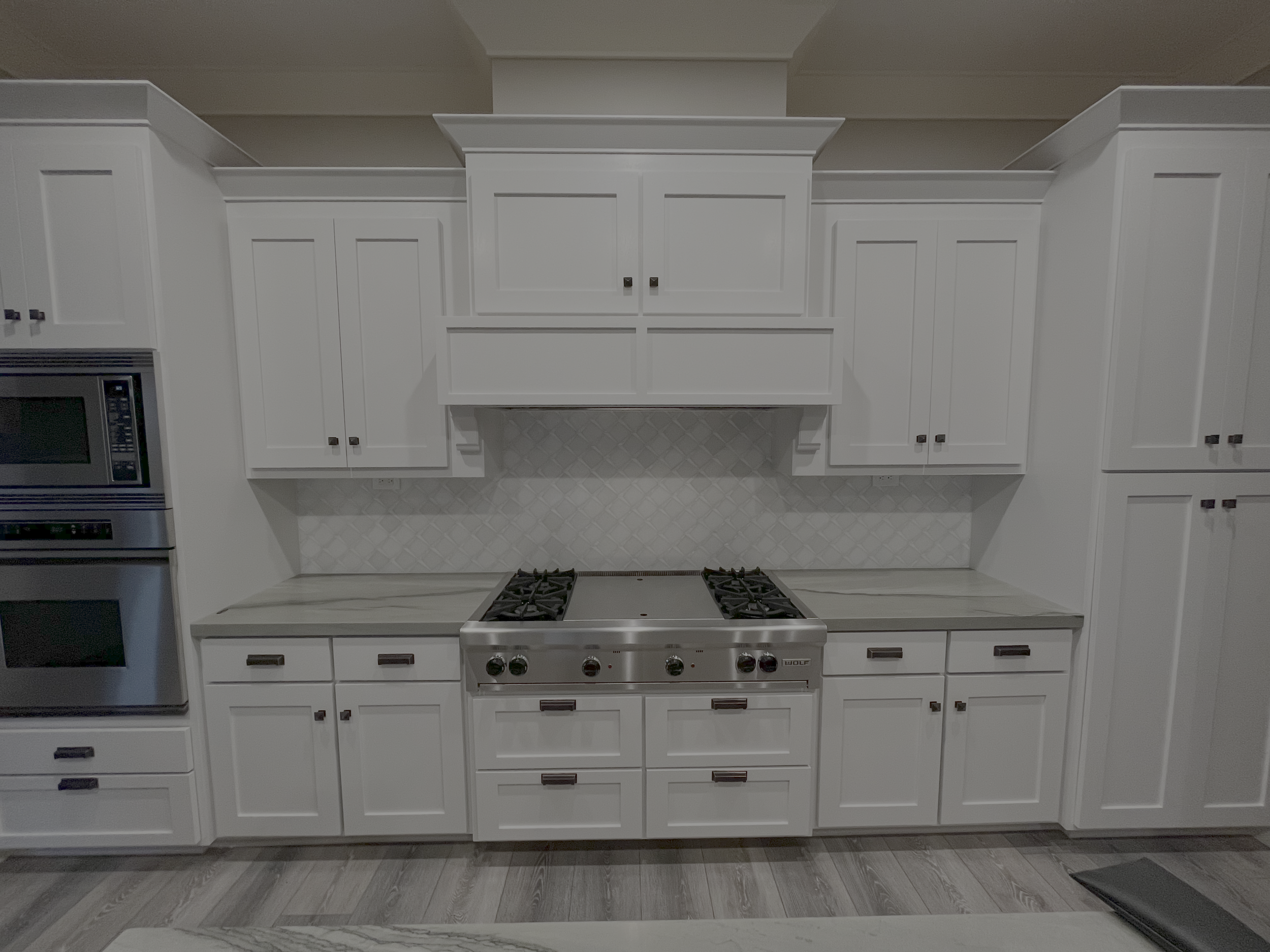 Finished kitchen with white cabinetry, tile backsplash, and range