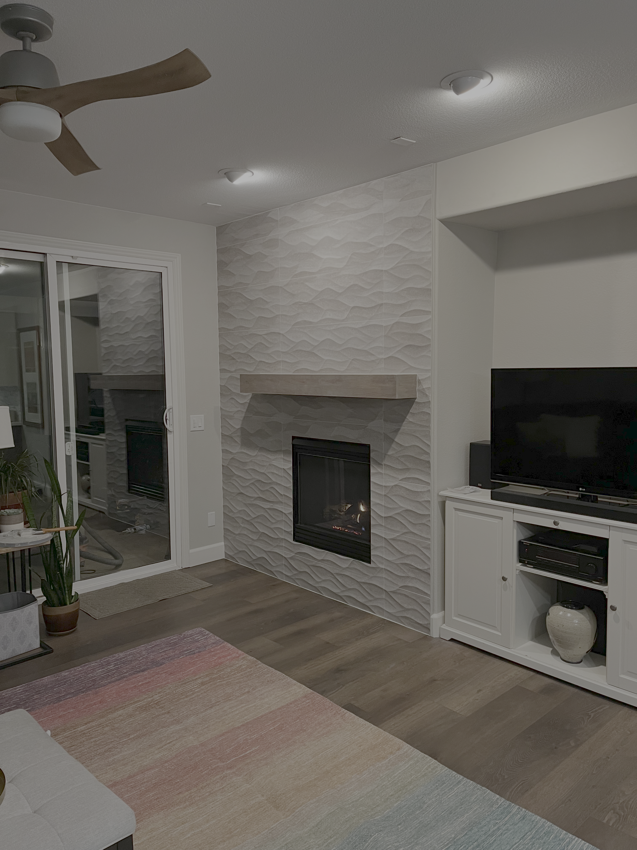 Completed fireplace surround with textured tile and wood mantel
