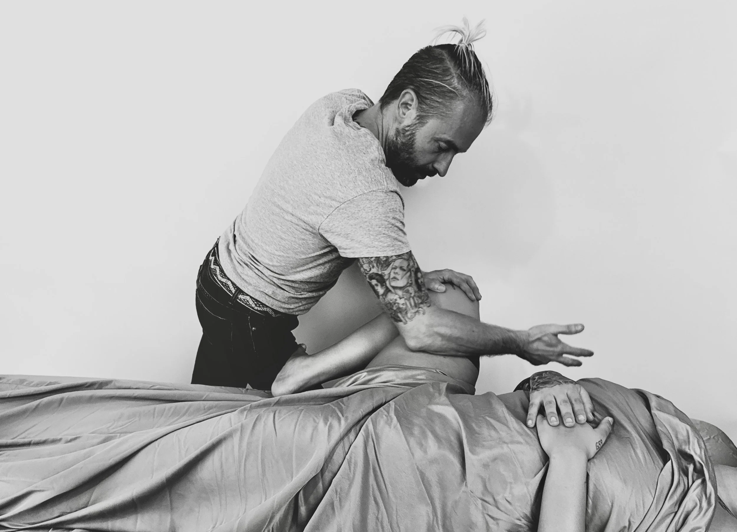 Josh demonstrates a massage technique on a person lying on a bed during a massage in New Orleans.