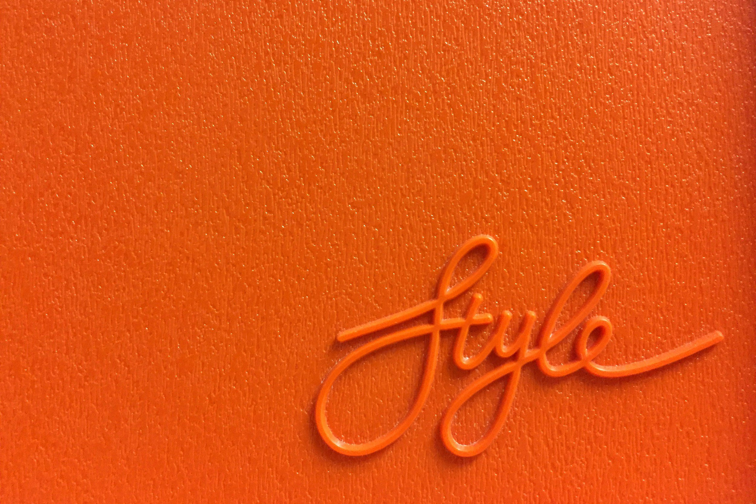 Close-up of an orange textured background with a small orange cursive logo that reads 'fylle'.