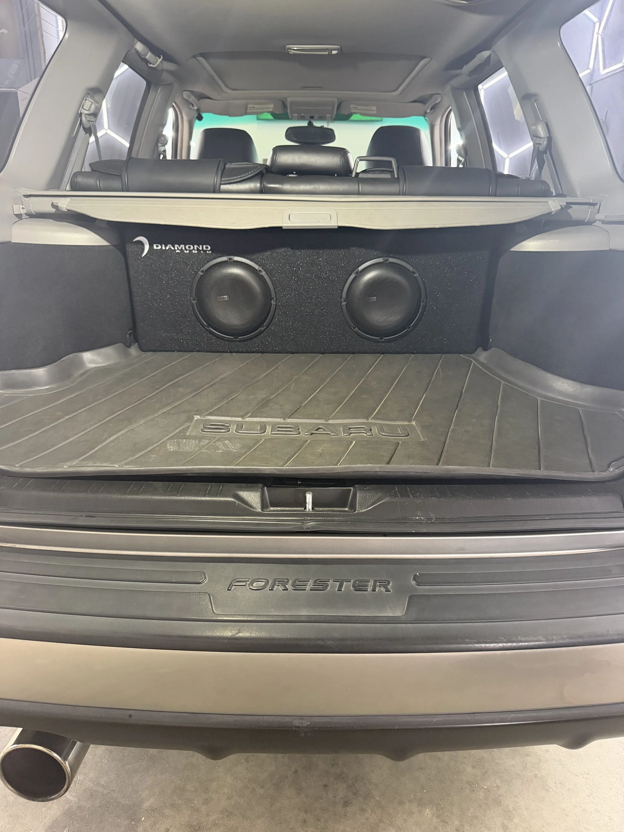The back of a silver Subaru Forester with a custom subwoofer in the trunk.