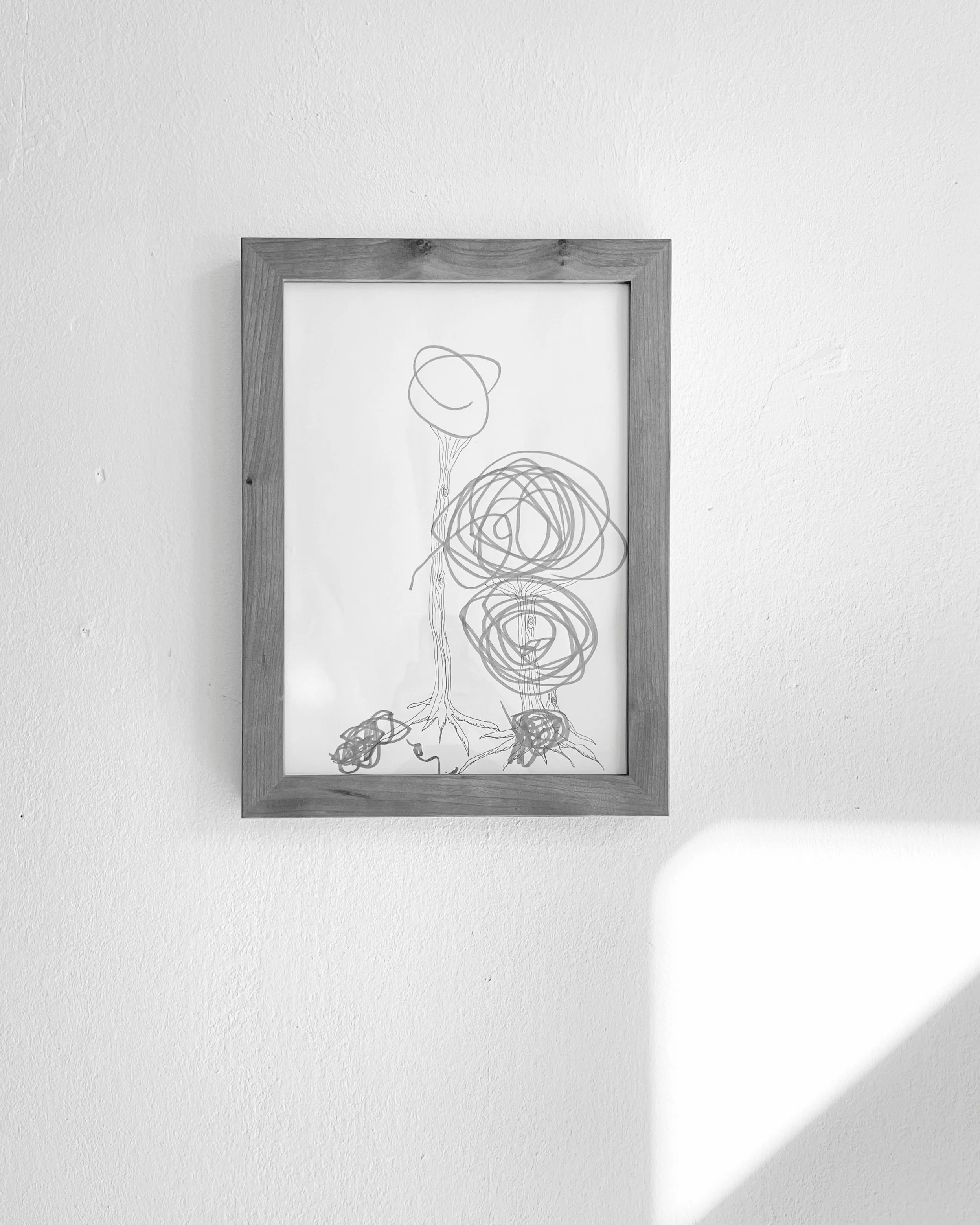 Kirschholzrahmen mit einer DIN A4-Kinderzeichnung darin an einer weißen Wand aufgehängt.