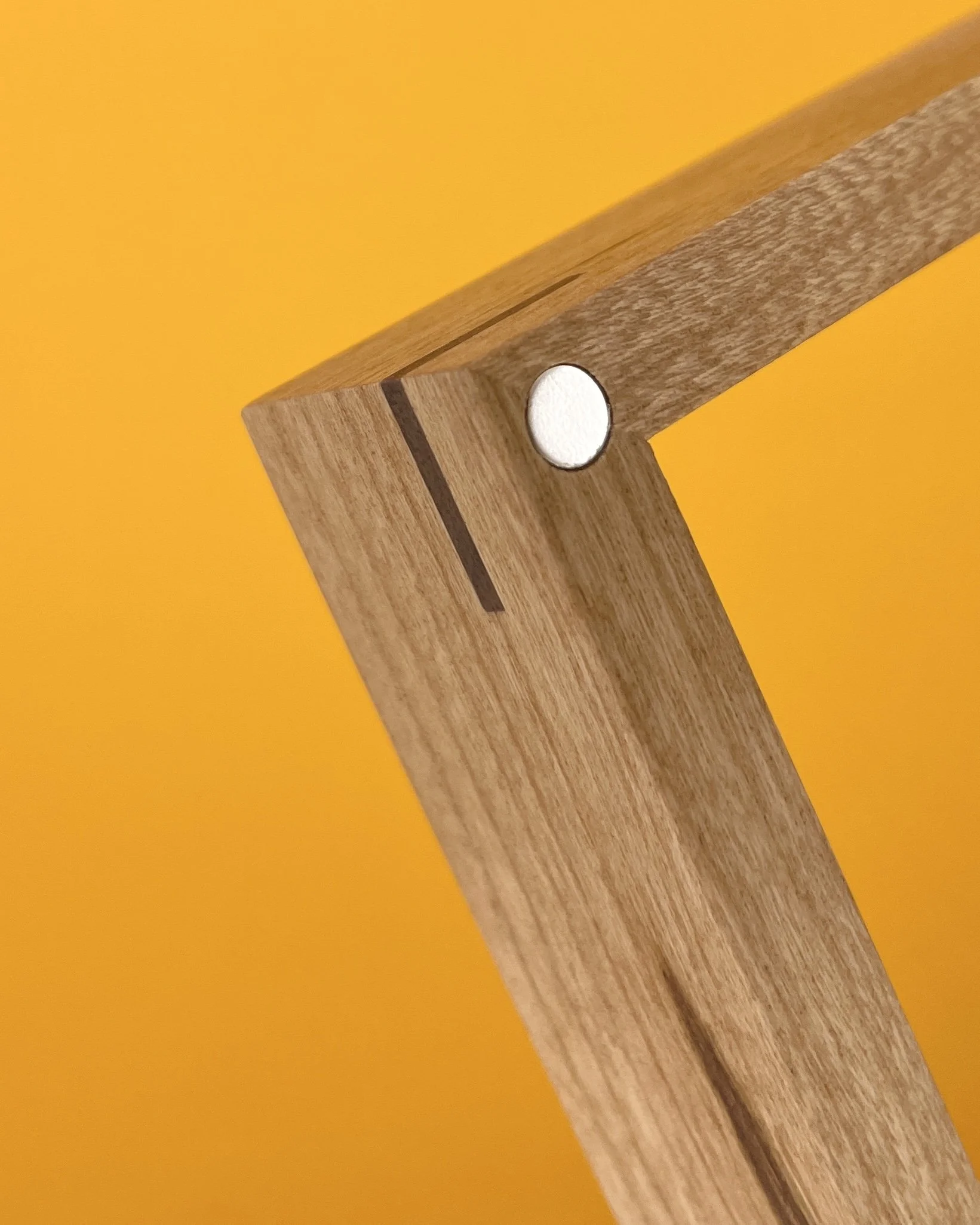 Detail eines Kirschholzrahmens (Ecke) mit Nussbaum-Eckenverstärkung und sichtbarem eingelassenen Neodym-Magnet.