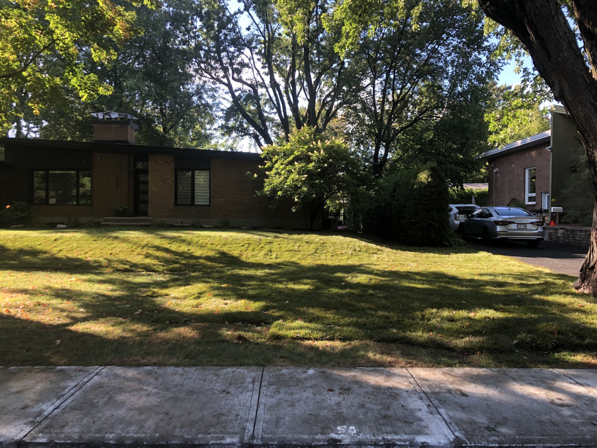 Un terrain avant avec de la tourbe fraîchement posée à Saint-Bruno et entourée de grands arbres.