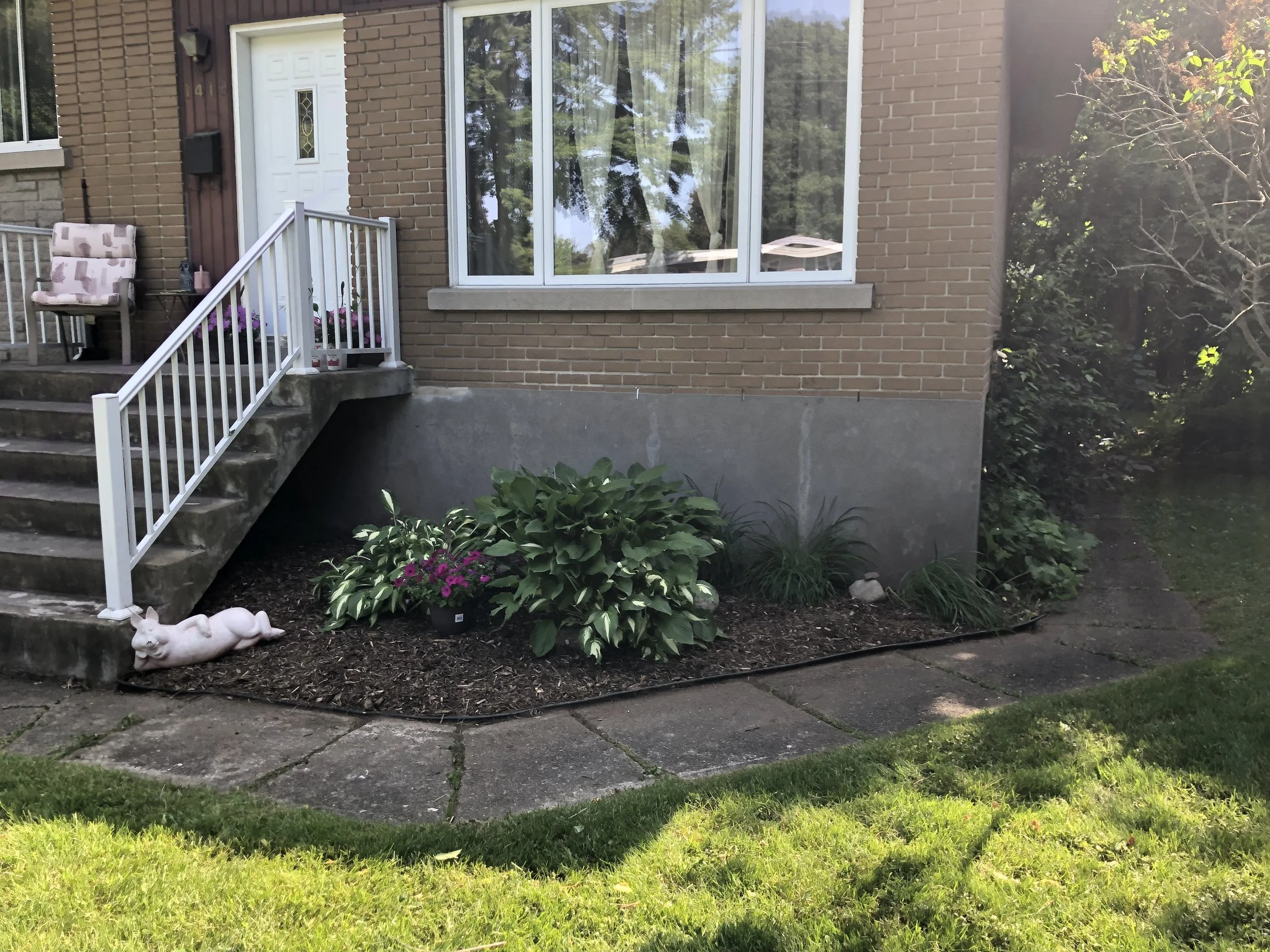 Une plate-bande de fleurs et de hostas avec un chemin devant une maison à St-Lambert.