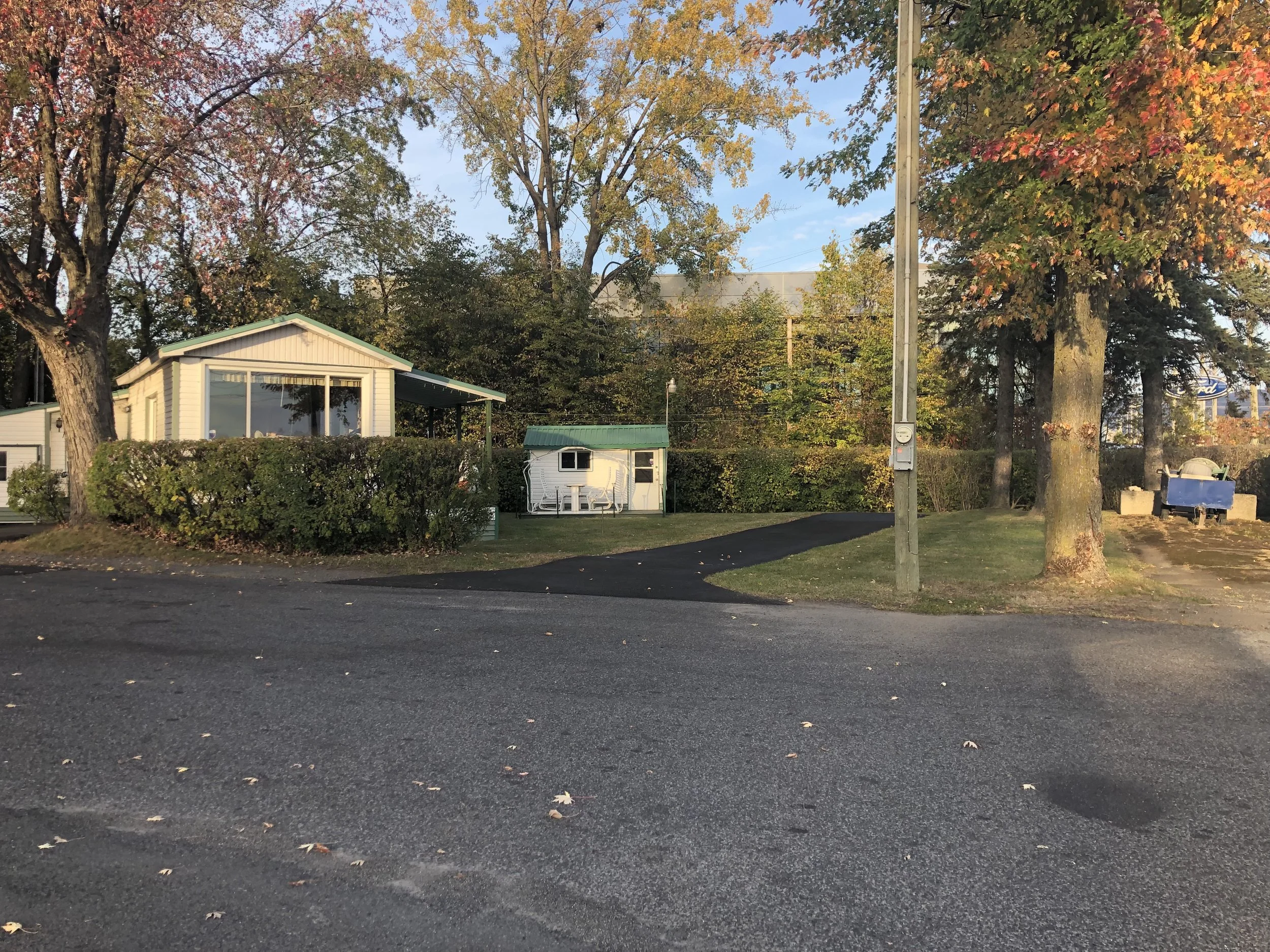 Une maison à Boucherville entourée de grands arbres et de feuilles tombées en automne.