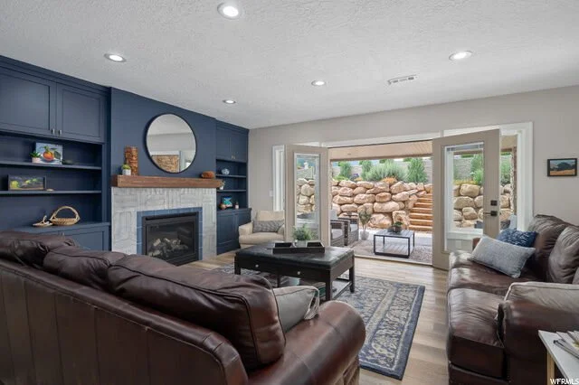 Living room with blue built-in shelves surrounding a fireplace, and large glass doors leading to a backyard with rock landscaping and stairs.