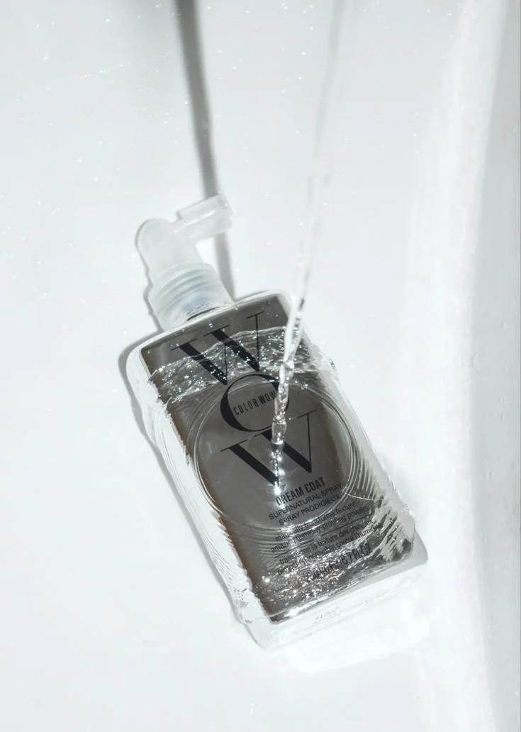 A bottle of WNT Color World Dream Coat Supernatural Spray being rinsed with water in a sink.