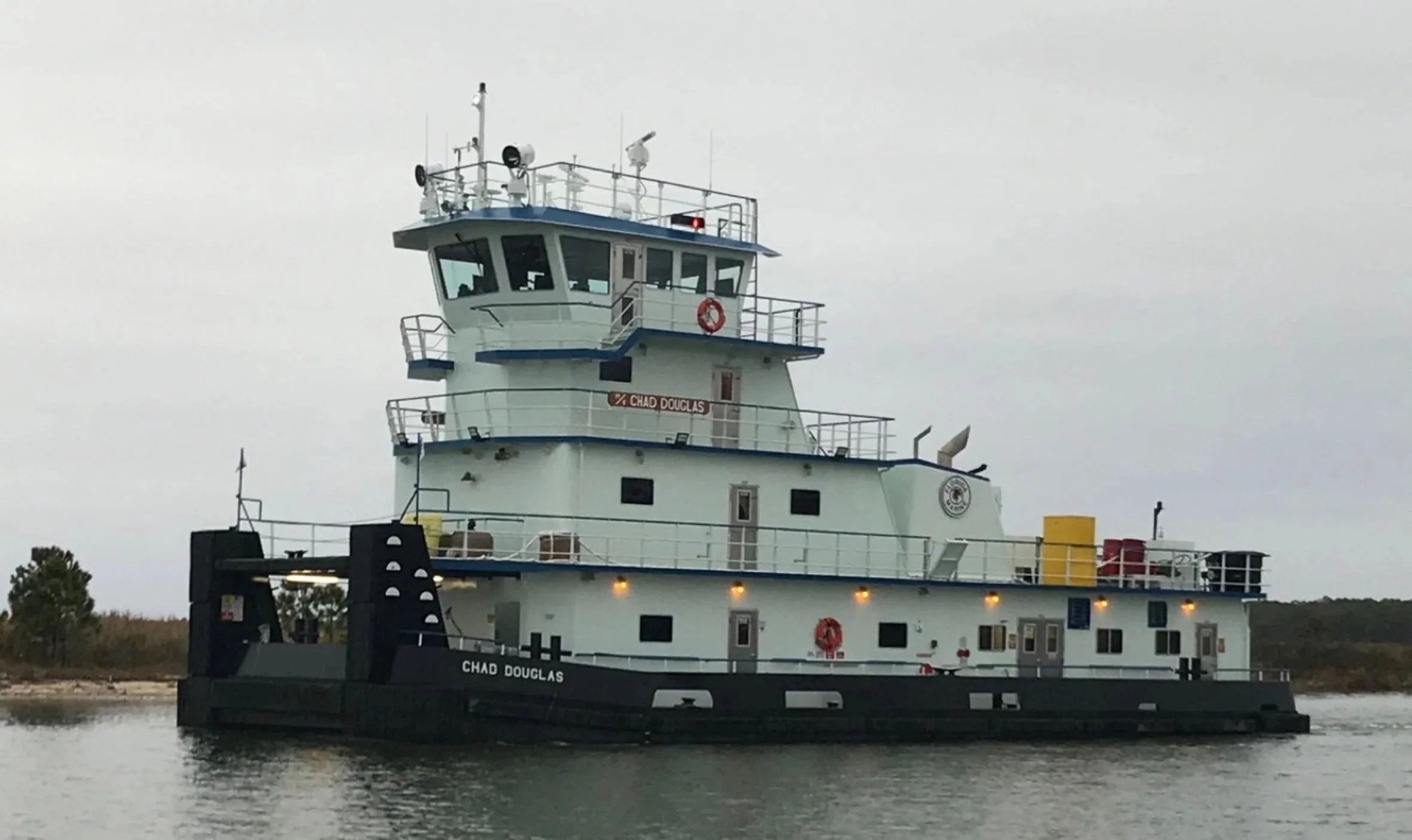 A large paddleboat-style vessel named Chad Douglas floating on water with an overcast sky in the background.