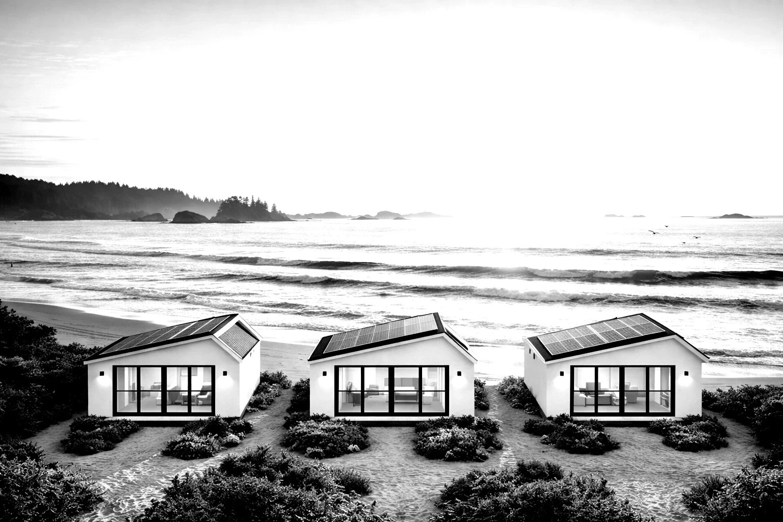 Three modern beach houses with solar panels on their roofs, facing the ocean, in a black and white photograph.