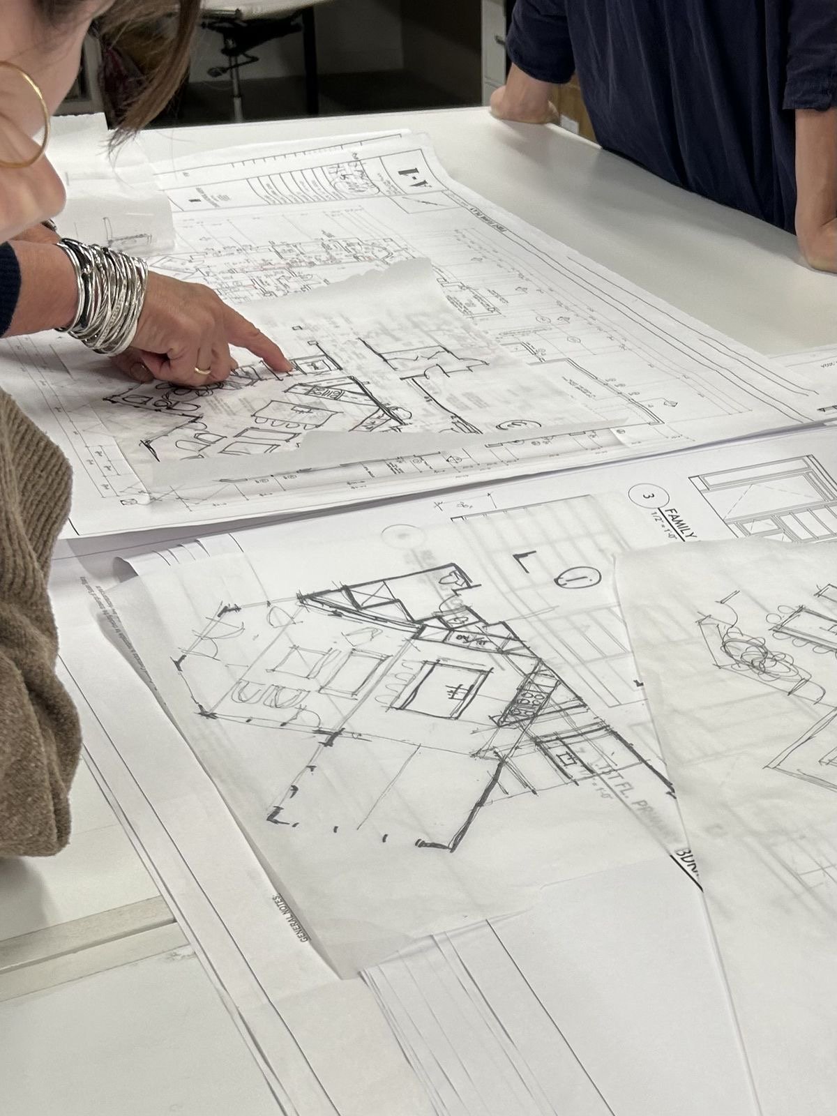People reviewing and discussing architectural blueprints on a table.