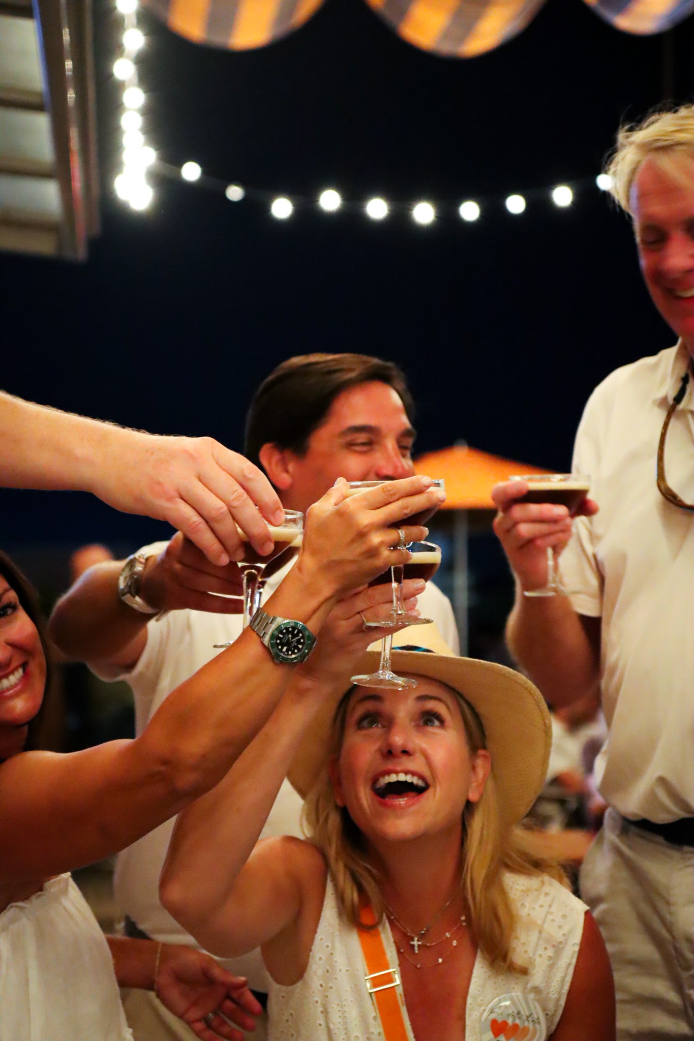 People celebrating and toasting with martinis, smiling and enjoying themselves at a festive night atop the Graduate Auburn at the War Eagle Supper Club bar.