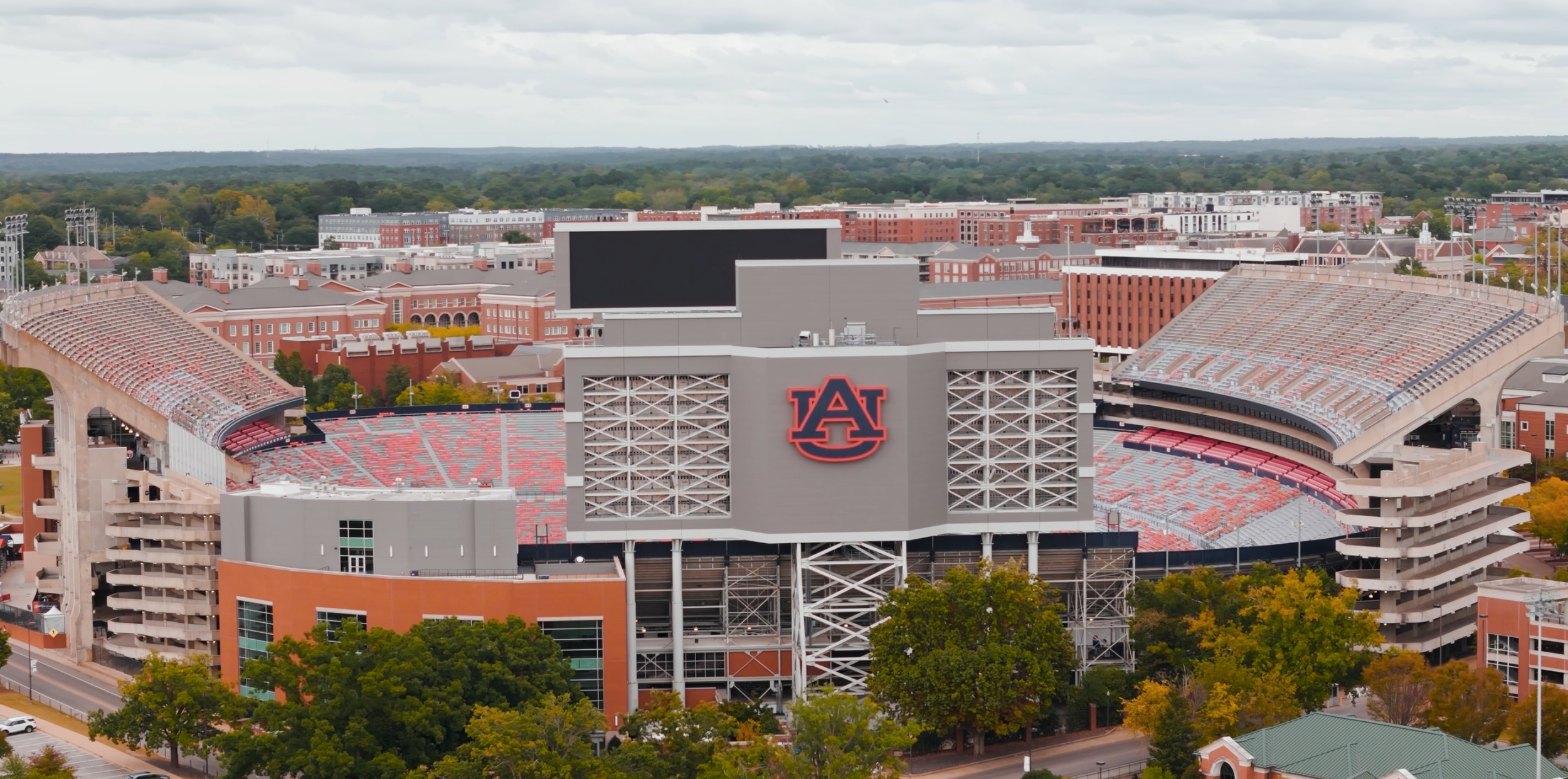 Aerial view of an Auburn University football stadium with the Auburn A logo, surrounded by trees and campus buildings