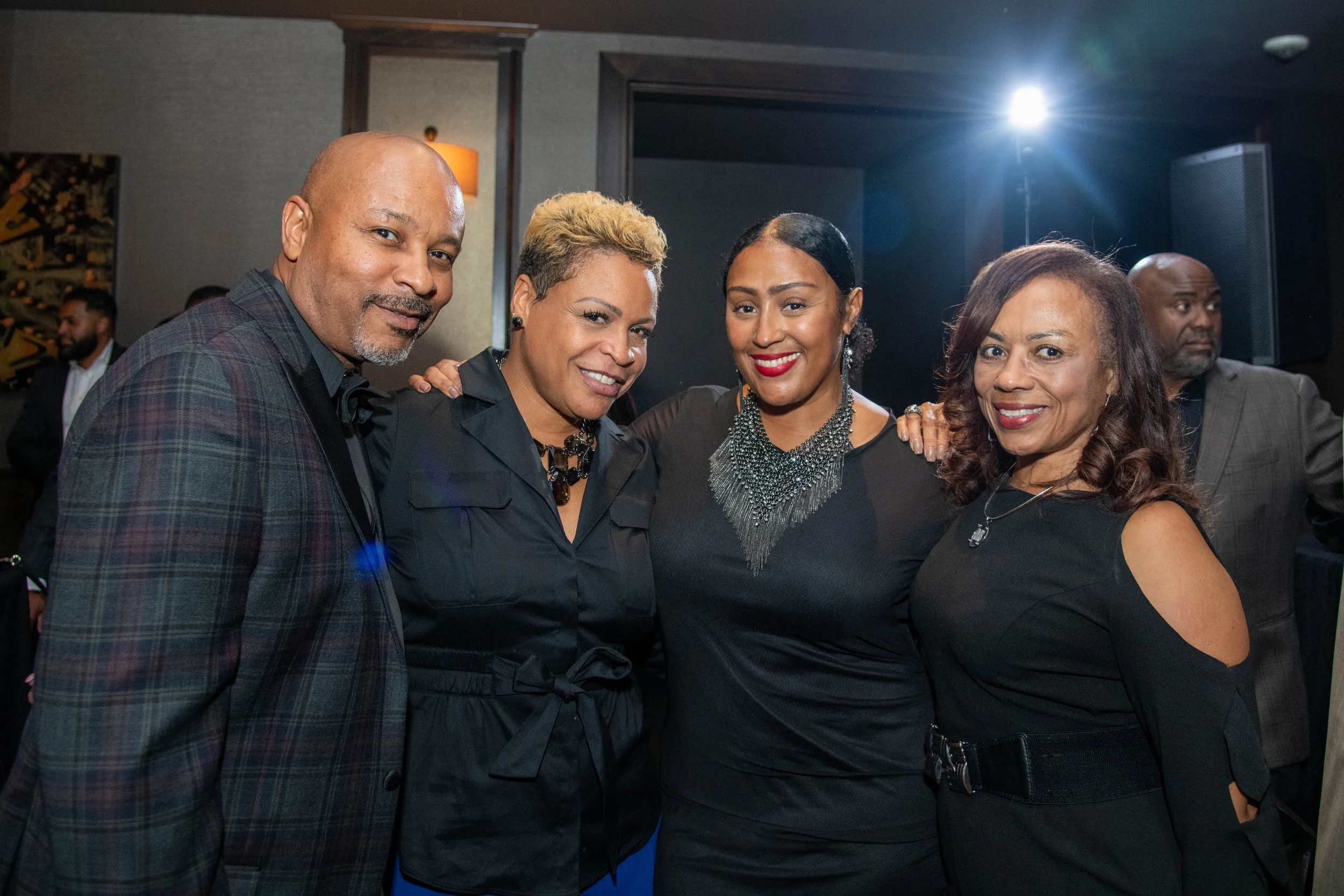 A group of five adults at a social event, posing together and smiling.
