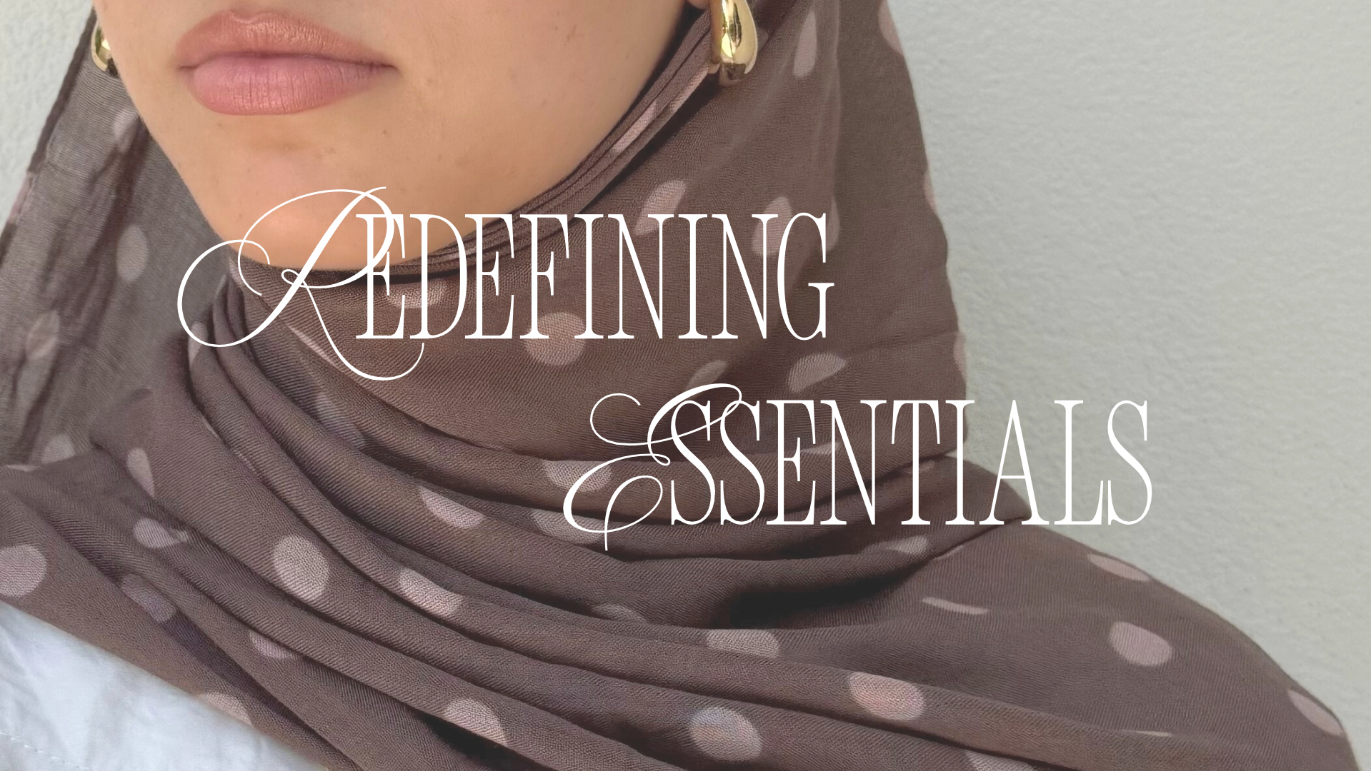 Close-up of a woman wearing a brown polka-dotted hijab with gold earrings and pink lipstick, overlaid with text reading 'Redefining Essentials'.