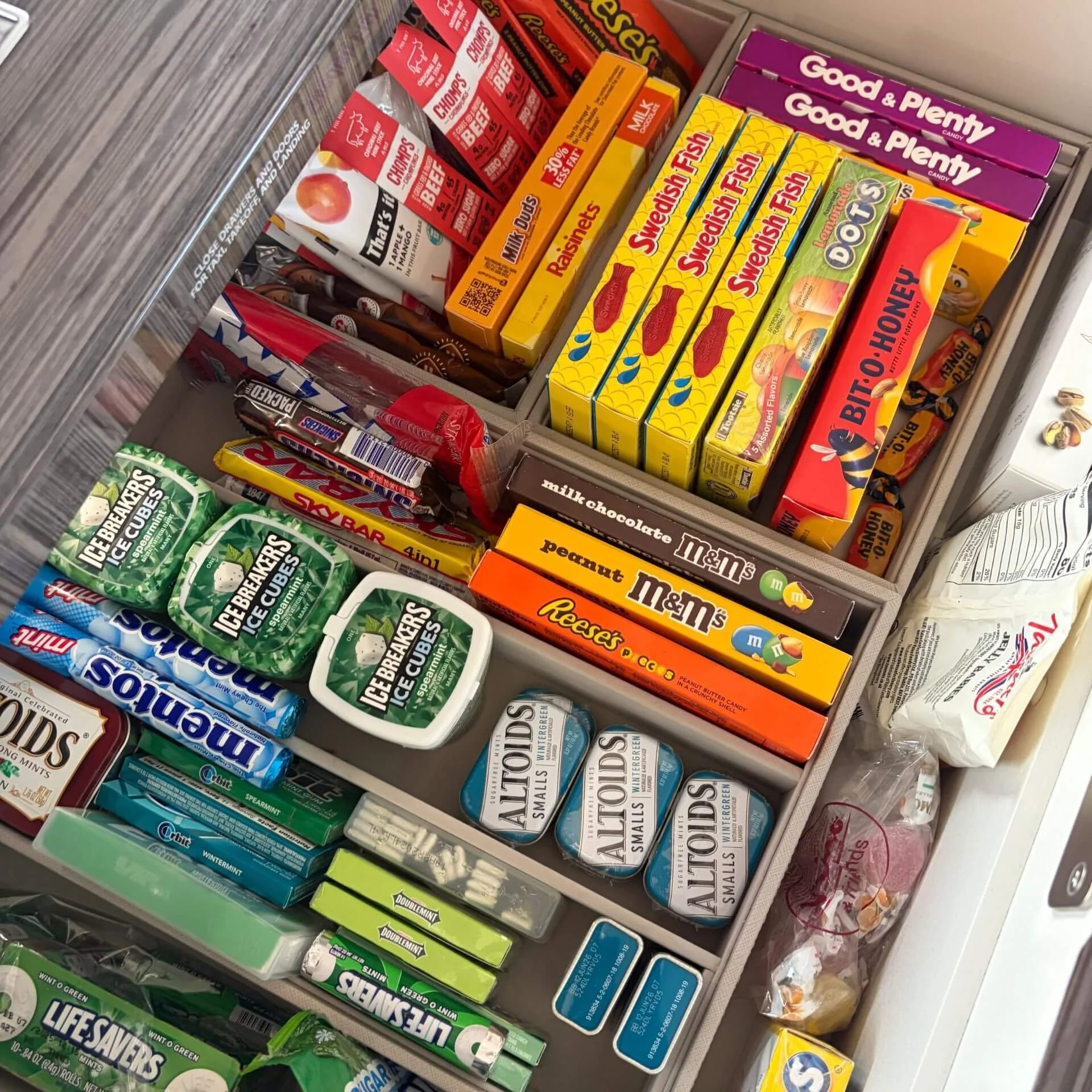 A drawer filled with various candies and gum, including Reese's, M&M's, Altoids, Icebreakers, and Swedish Fish.