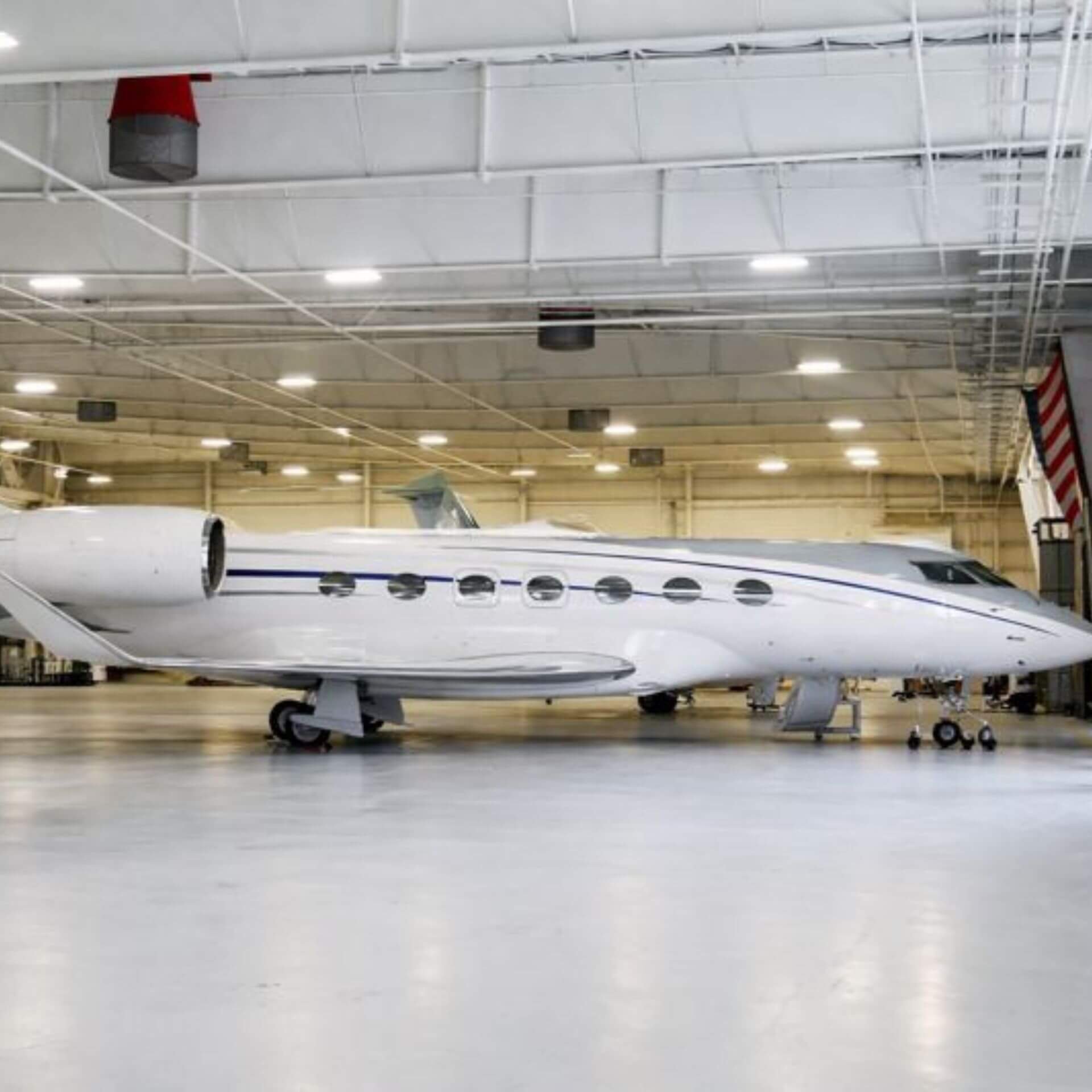 Inside a hangar with a white private jet parked on the tarmac.