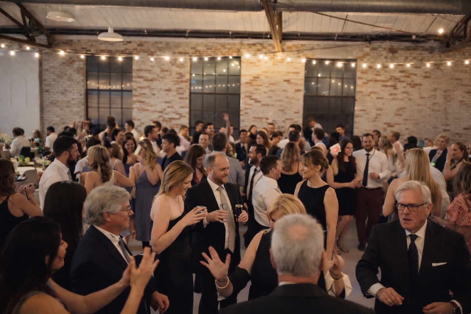 Wedding guests cheering and raising hands on a packed dance floor in High Point, North Carolina.
