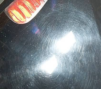 Part of a Coca-Cola can with a flame design on a reflective black surface.