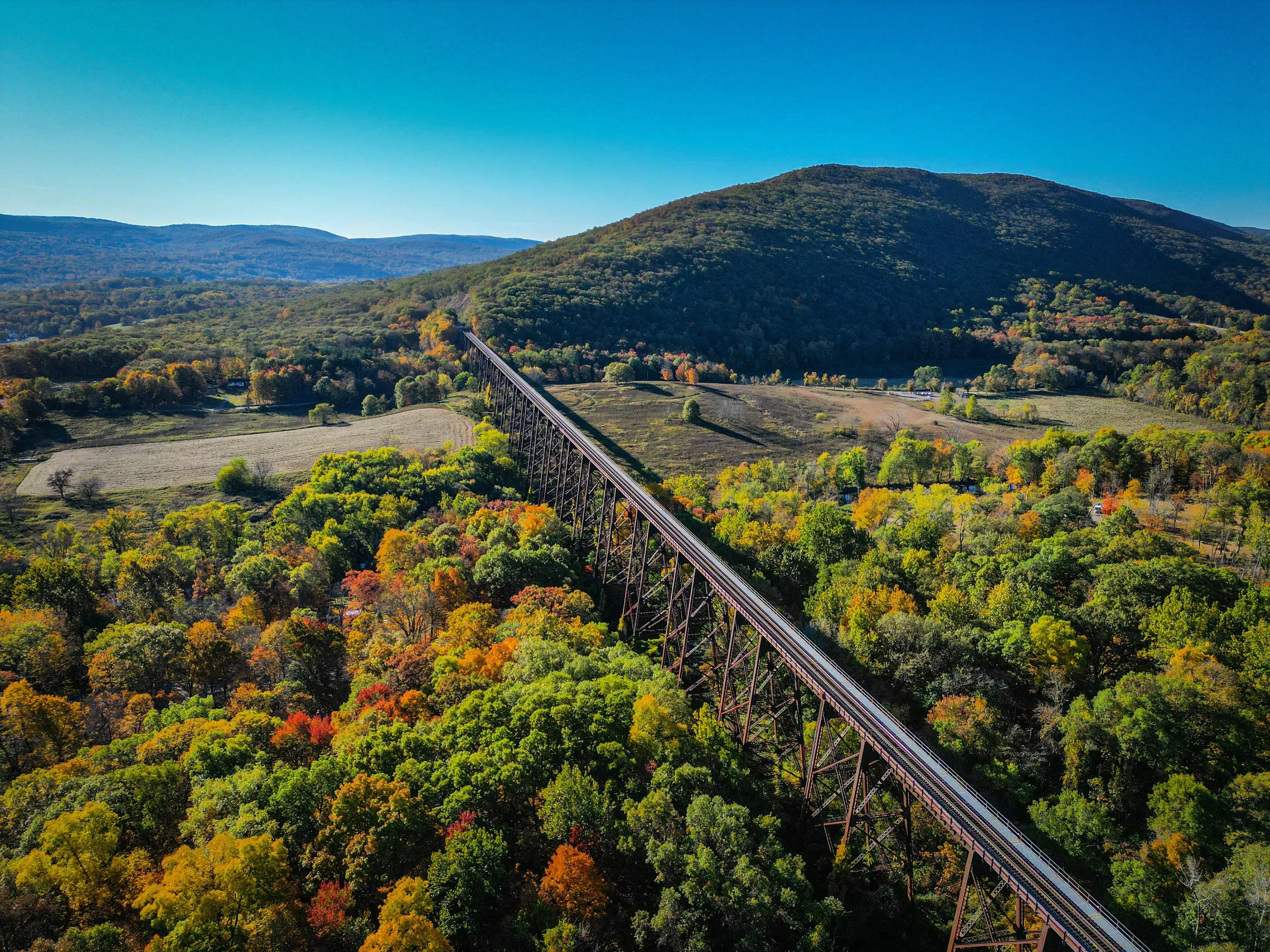 Scenic Hudson Valley landscape of the Moodna Viaduct with a bridge crossing a wooded valley in autumn.