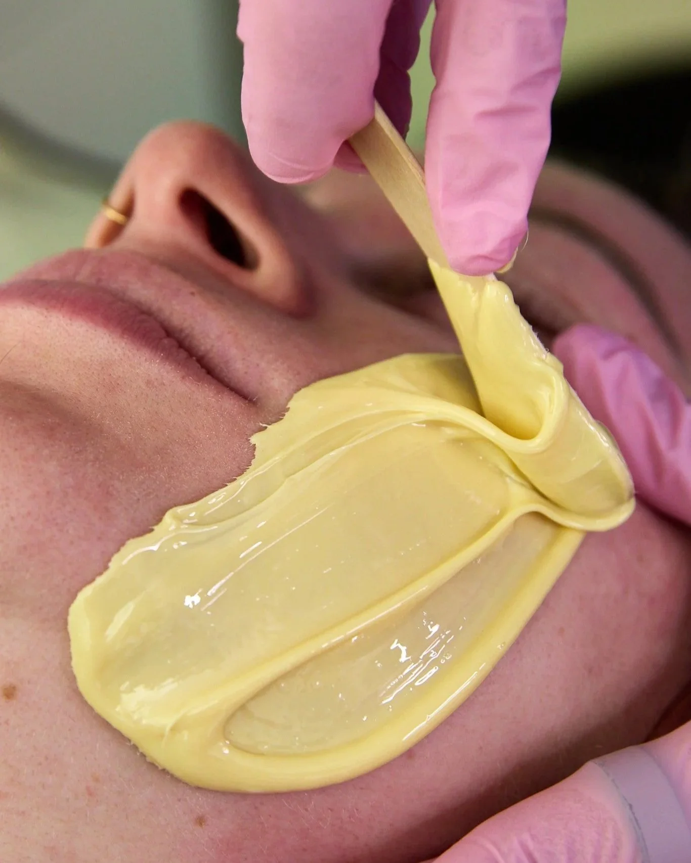 Rachel applies fresh wax to a clients cheek.