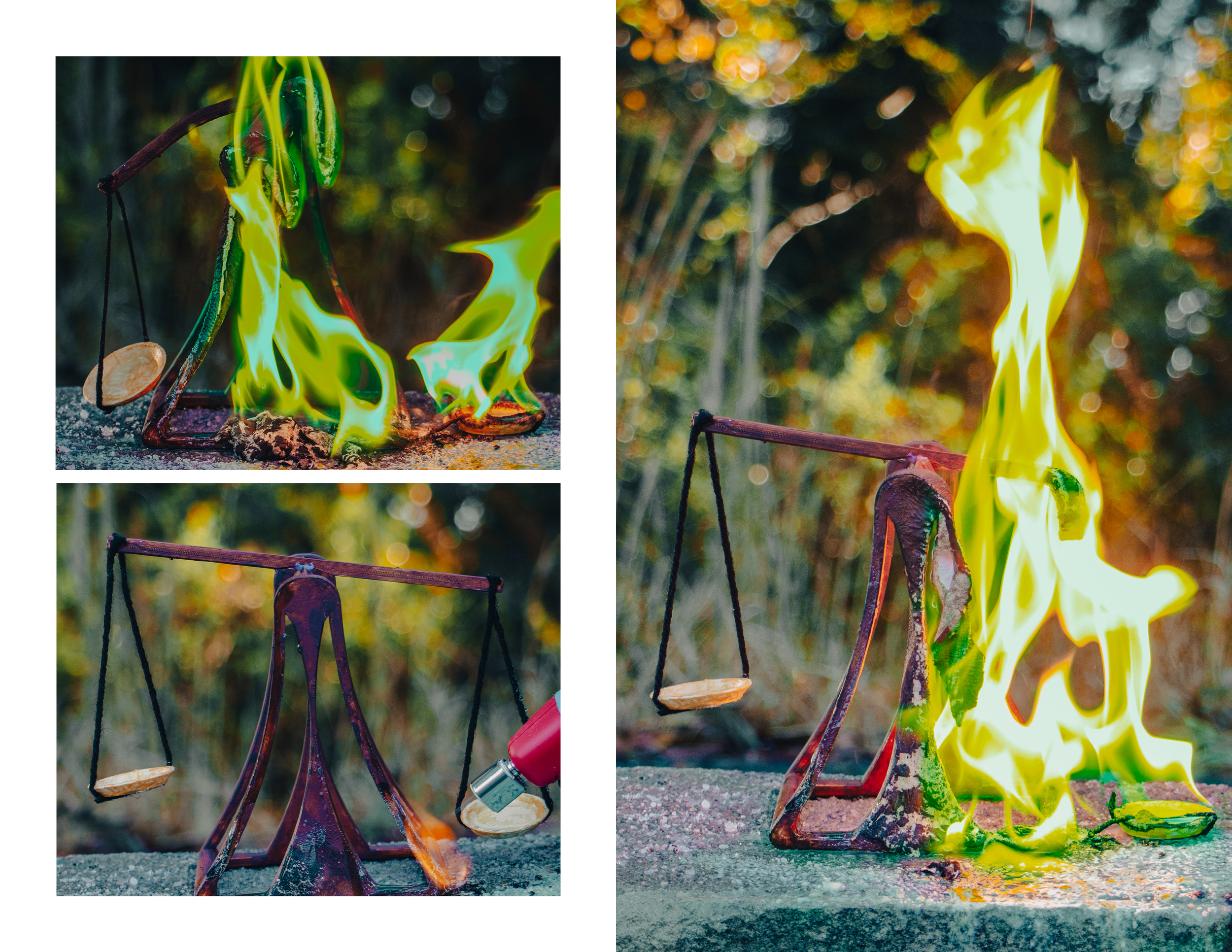 A 3D printed sculpture of a balance, is on fire with flames engulfing it. The setting appears outdoors with a blurred natural background. The scale is mounted on a concrete surface, and the flames are bright yellow and green.
