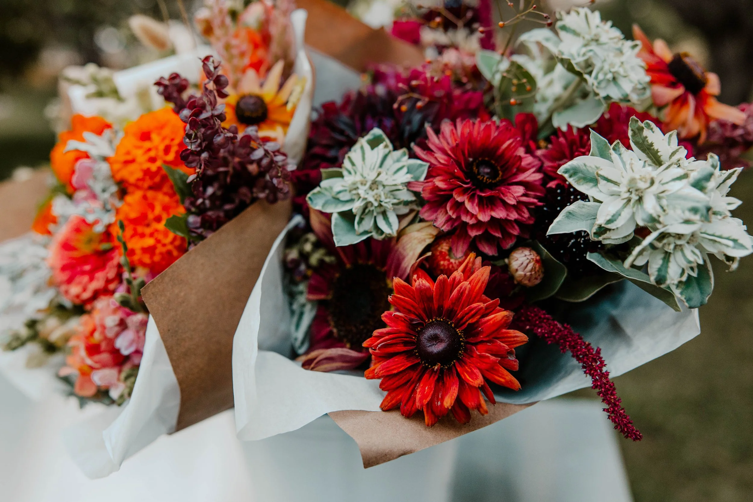 A close up photo of a bucket of mixed flower bouquets in reds and oranges.