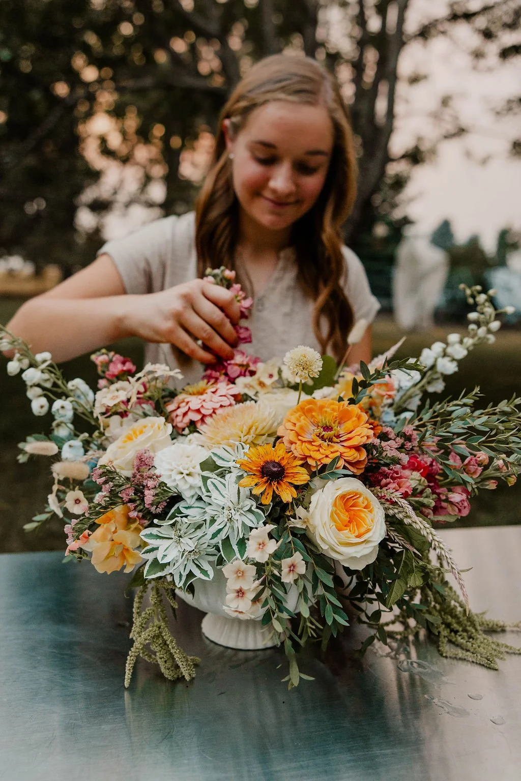 Woman arranging flowers on a table outdoors at sunset