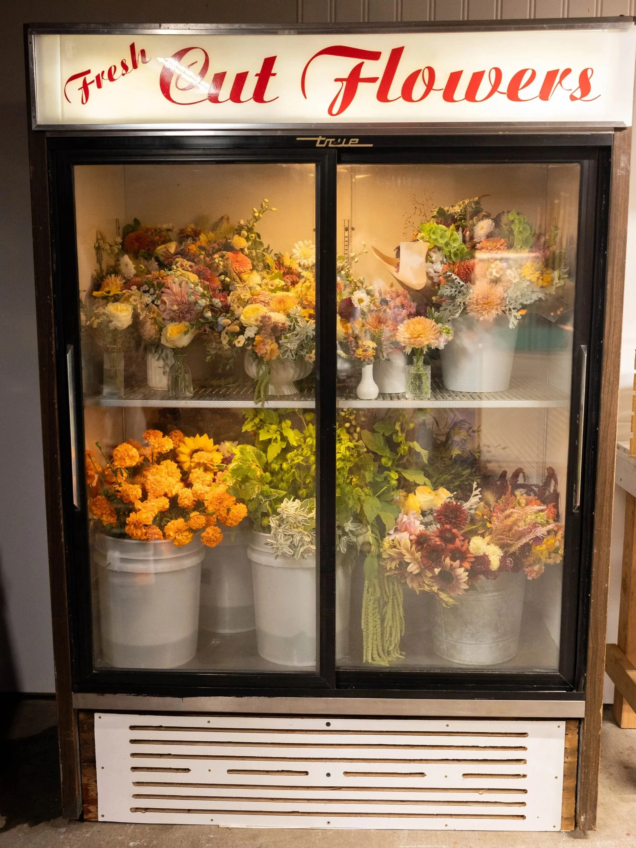 Sliding door refrigerator with white buckets of colorful flowers in orange, green, pink, red, and white, with the words Fresh Cut Flowers at the top.