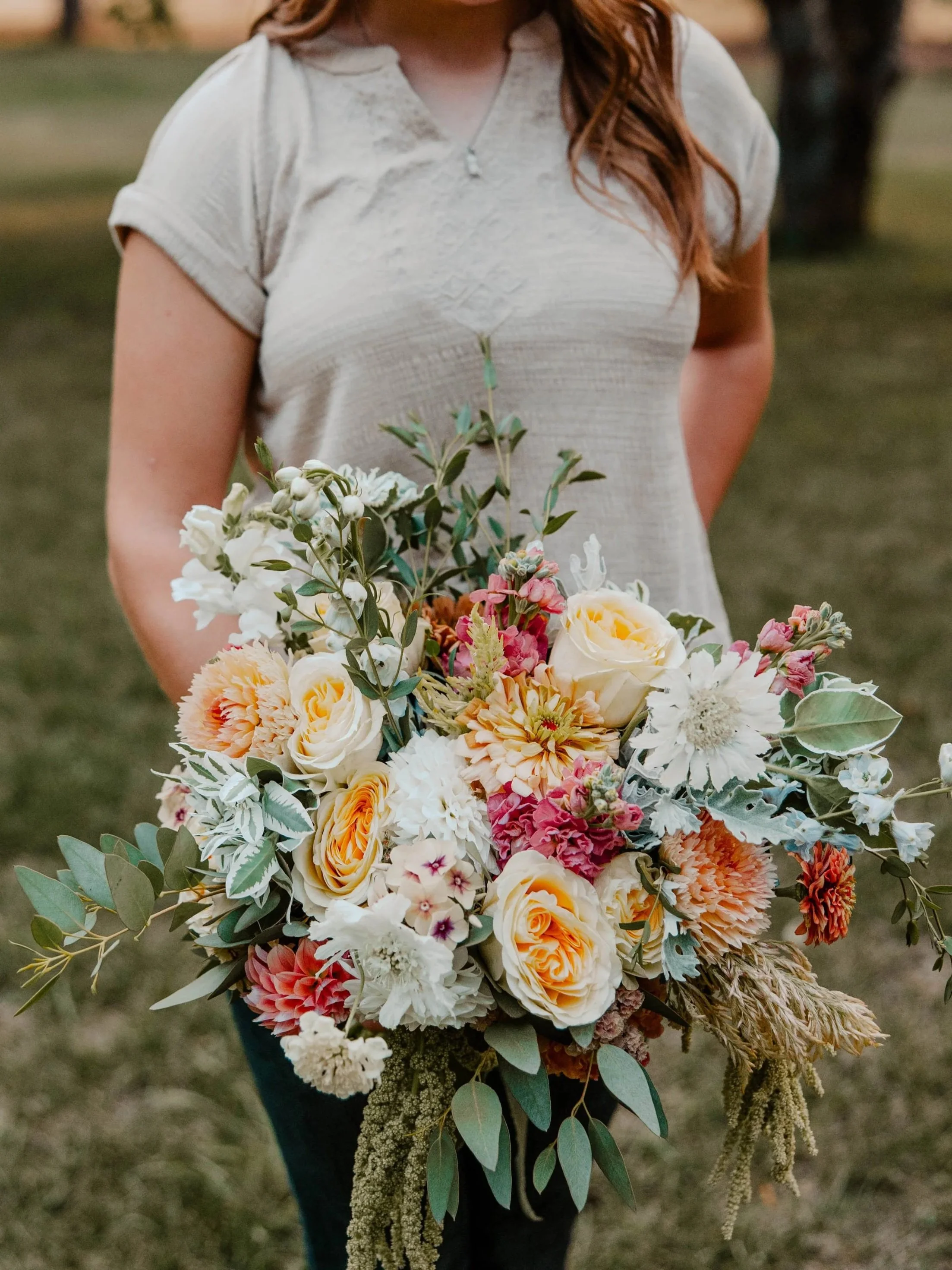 Woman holding a bridal bouquet of flowers with light yellow roses