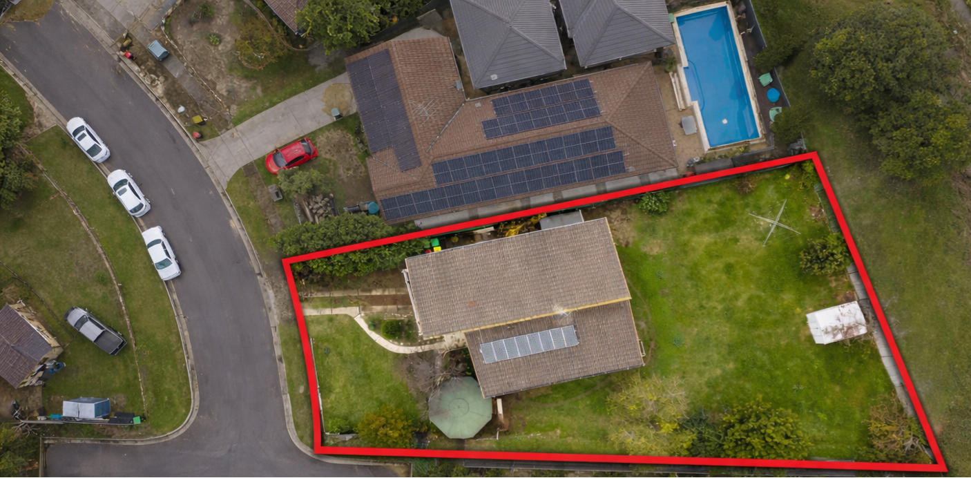 Aerial view of a residential backyard outlined in red, showing a house with solar panels, a swimming pool, a small white shed, and a large grassy area, with neighboring houses and parked cars nearby.