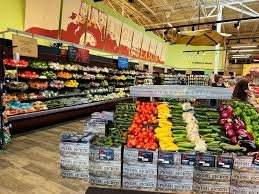 Grocery store produce section with apples, oranges, and other fruits.