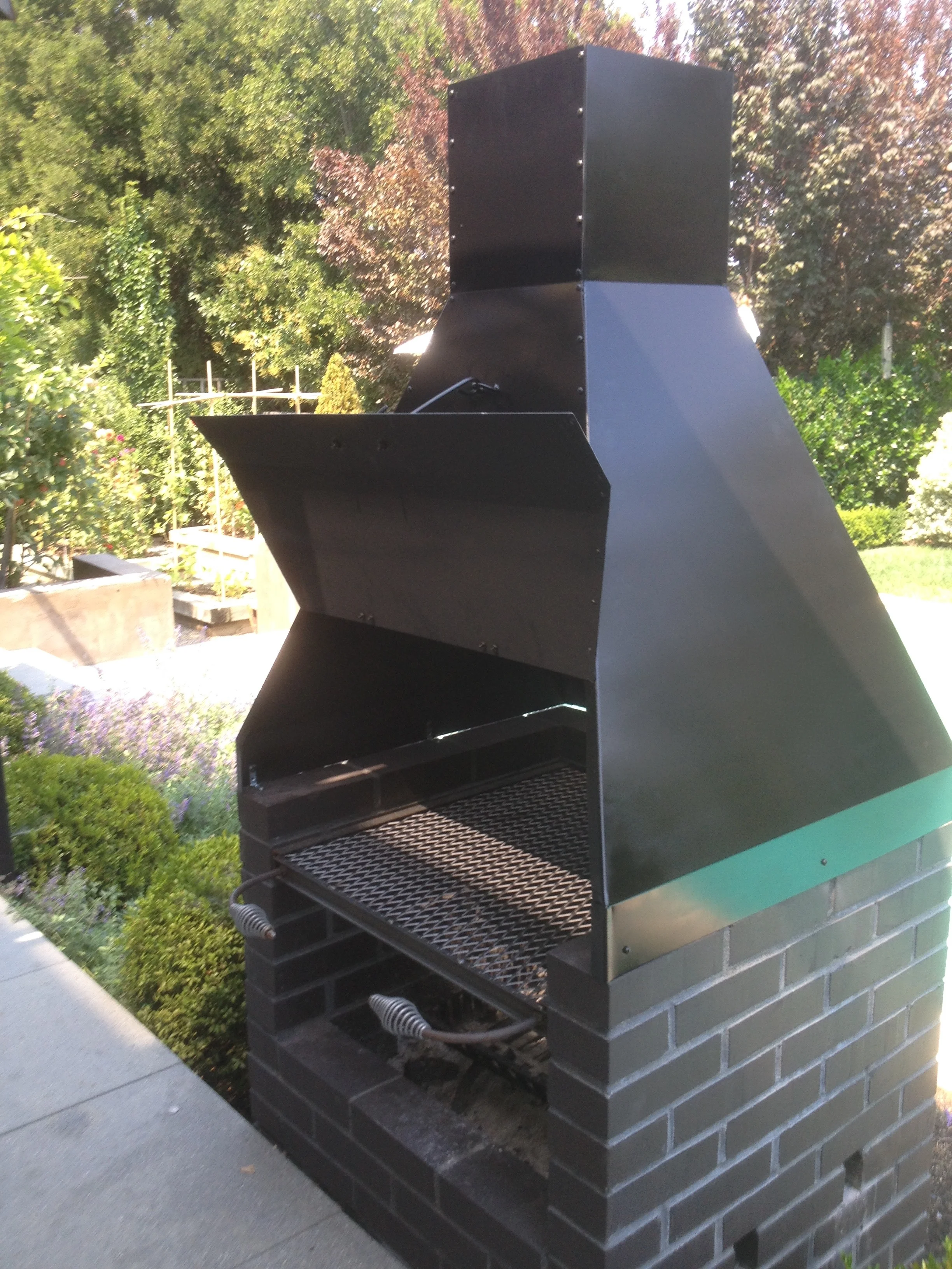   Outdoor Fireplace Chimney and Grill   This barbecue grill and chimney accents a client's outdoor brick fireplace. The removable grill slides out on tracks. The chimney directs smoke up and away from the house. This grill and chimney transformed the
