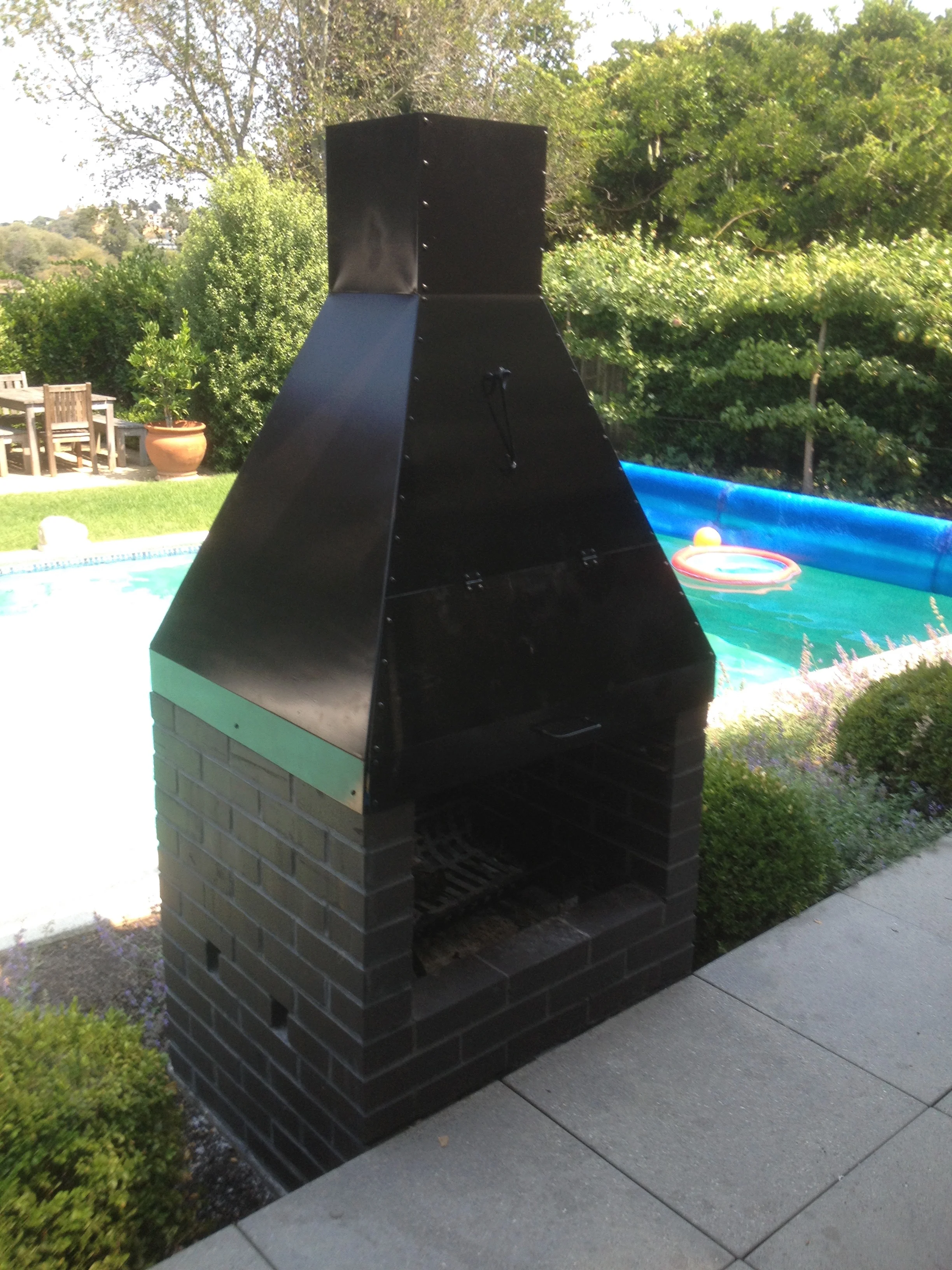   Outdoor Fireplace Chimney and Grill   This barbecue grill and chimney accents a client's outdoor brick fireplace. The removable grill slides out on tracks. The chimney directs smoke up and away from the house. This grill and chimney transformed the