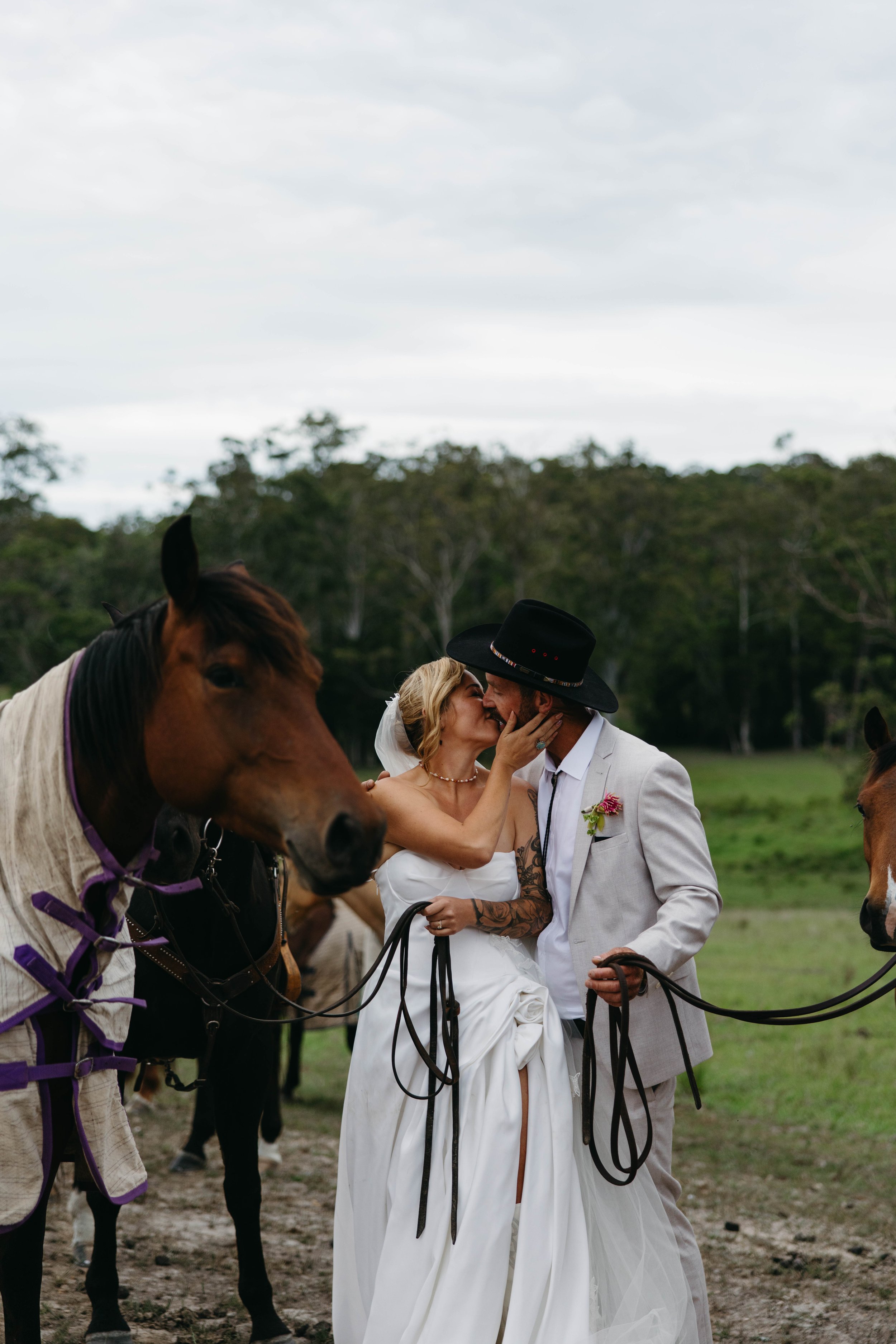Bride and groom share a kiss surrounded by horses at a Barrington Coast wedding, NSW
