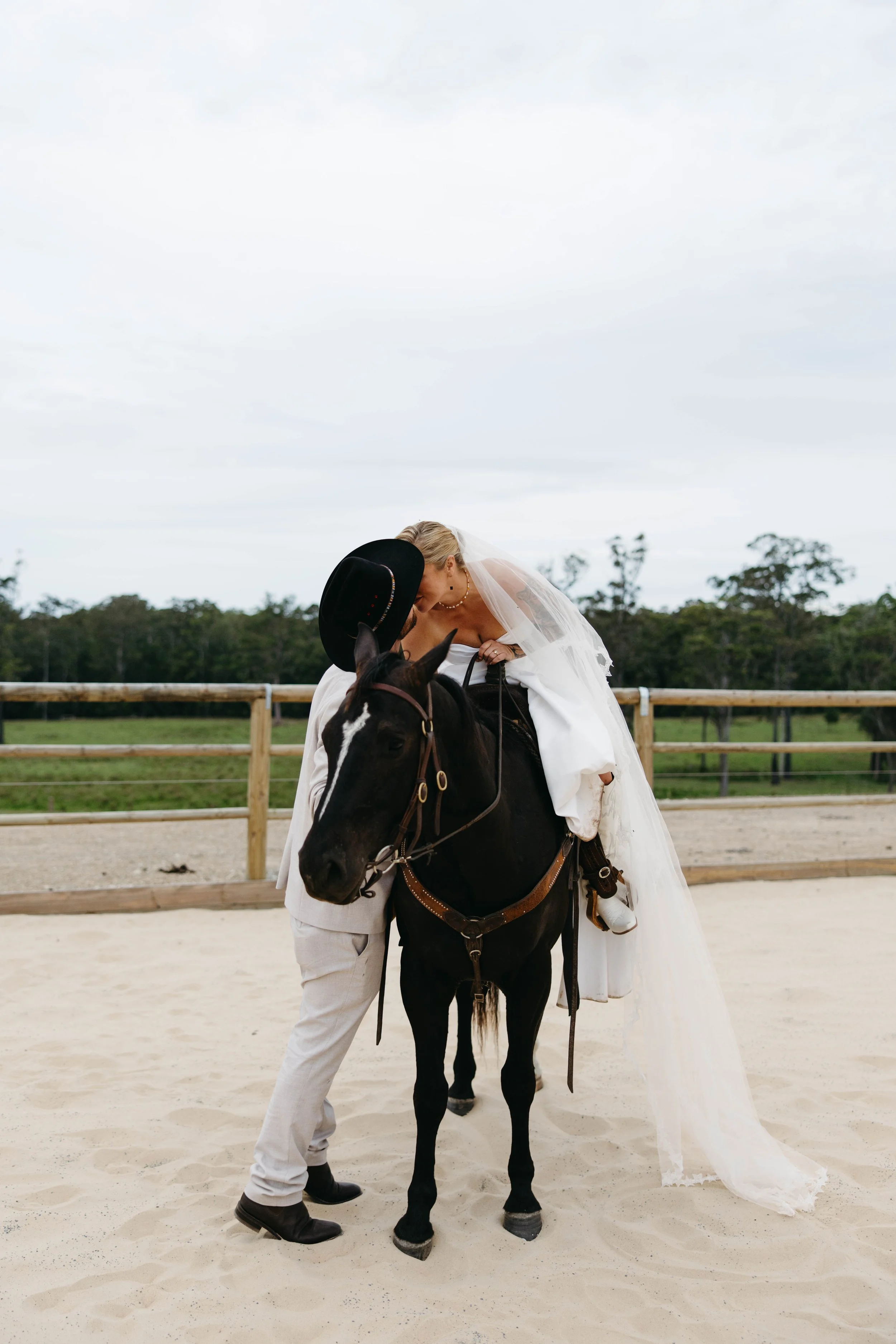 Bride and groom sharing a kiss on horseback at a Barrington Coast wedding, NSW