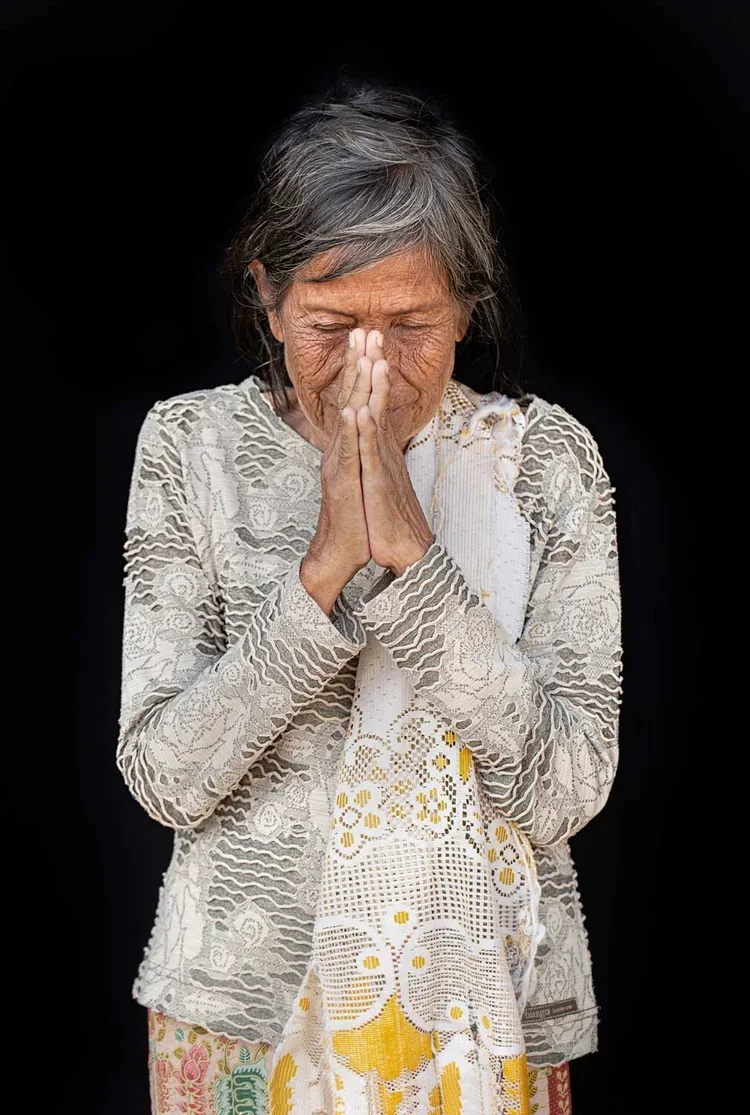 SokChan age 75: *I met SokChan outside the interior gate of the temple. She lives on the street but said she frequently sleeps near the reclining Buddha or in the stupas (tombs). She drinks water from the pond and relies on handouts for food but was 