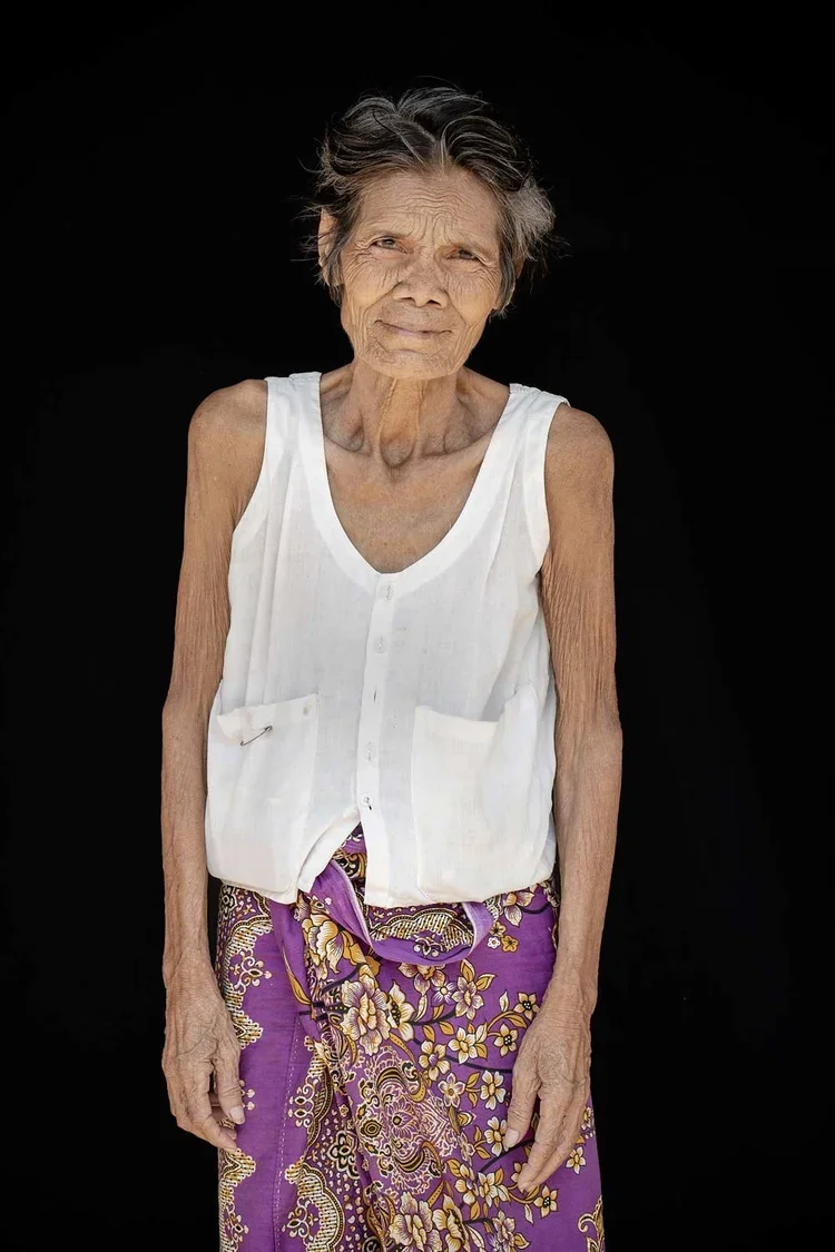 SanNum age 75 : "I have lived in Phnom Penh my entire life." *SanNum's home is a wooden, slatted platform, no walls. This is where she sleeps and works, selling snacks to children and passersby. "I was married at age 19. My marriage was arranged by m