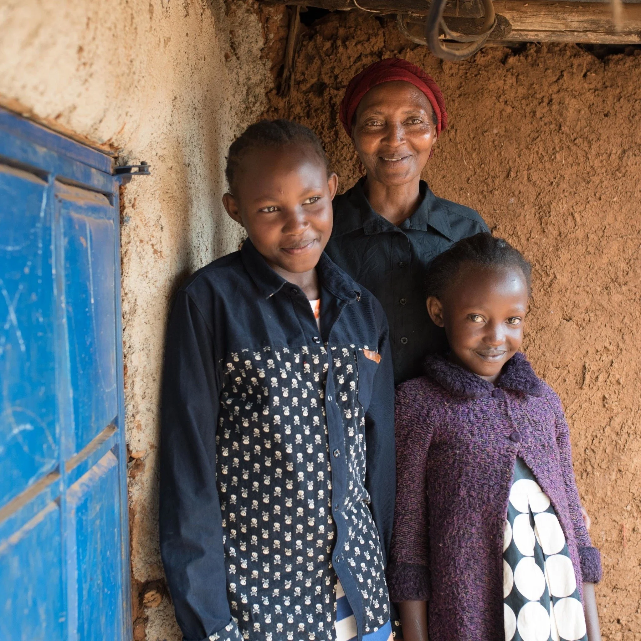 Caregiver with two children smiling shyly