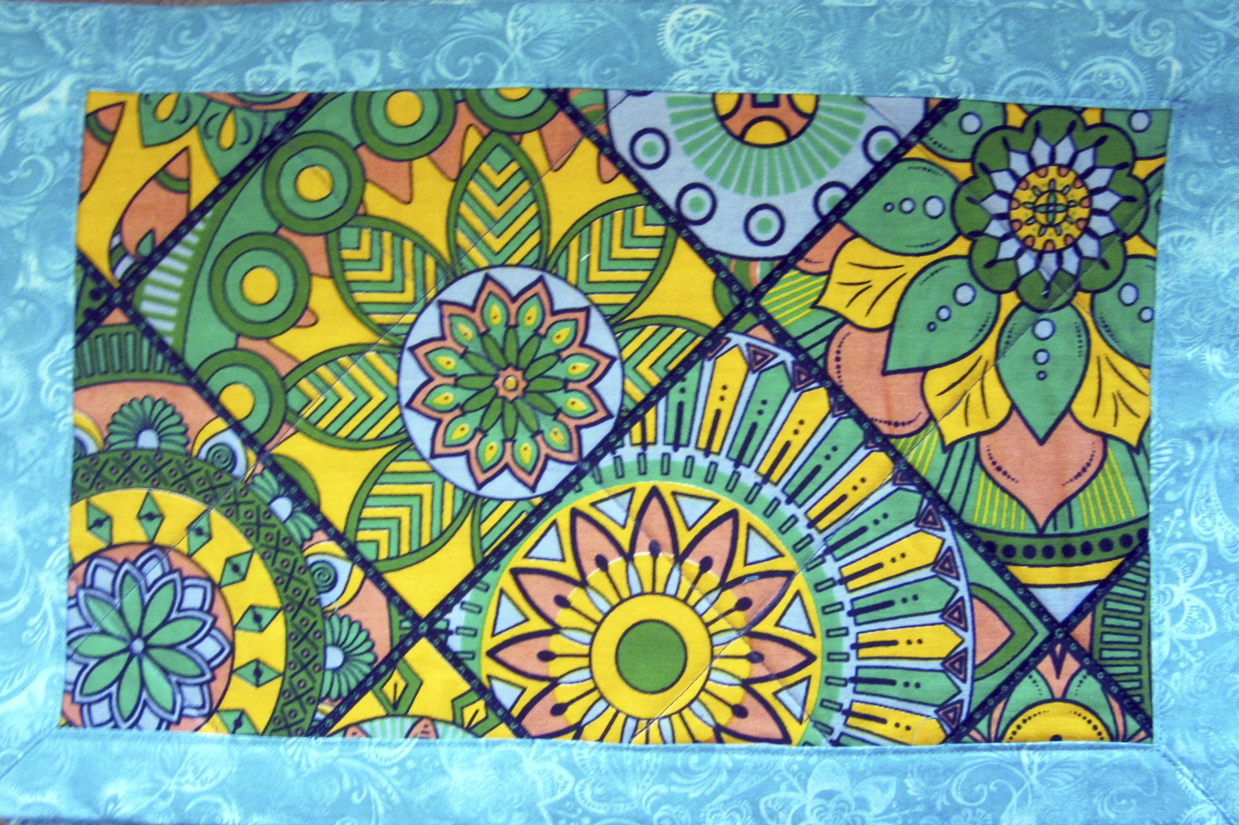 Green & turquoise placemat. 
17.5” x 13.25”   $45 a pair 
Made with authentic African wax-printed fabric, 100% cotton.  
WASHING INSTRUCTIONS:  Cool water, air dry, can be ironed. 