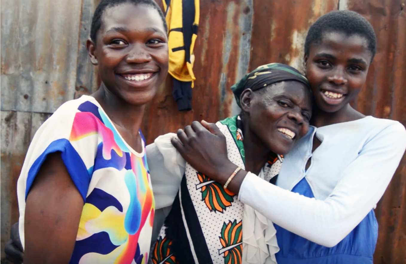 Smiling mother hugged by her two happy adopted daughters