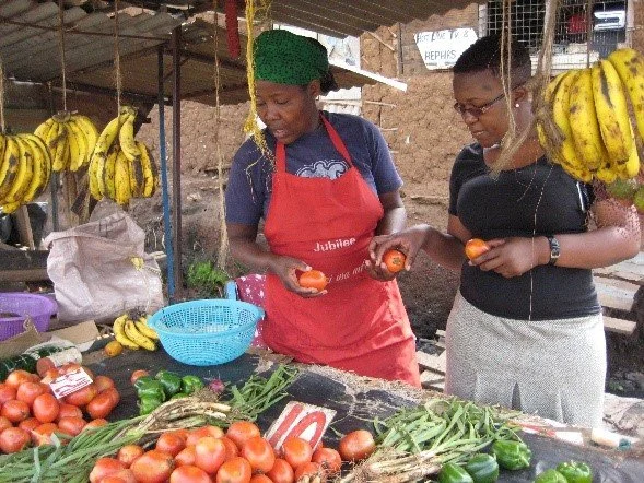 Staff with a community member at her market stall.