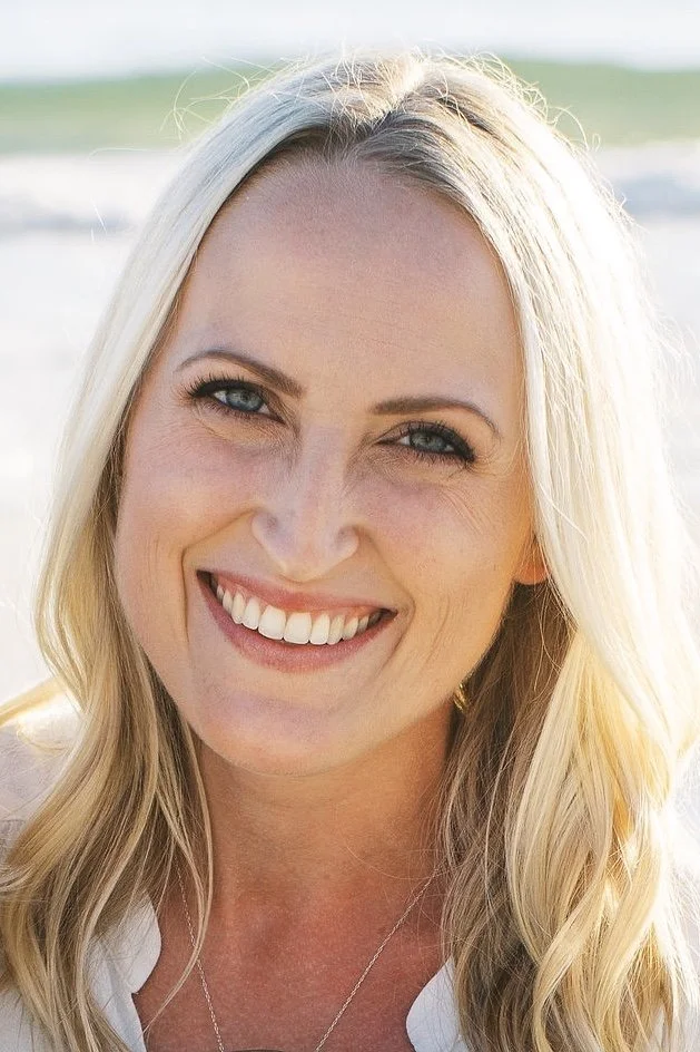 Close-up of a smiling woman with blonde hair, blue eyes, and a bright outdoor background is board member Anna van Rennes.
