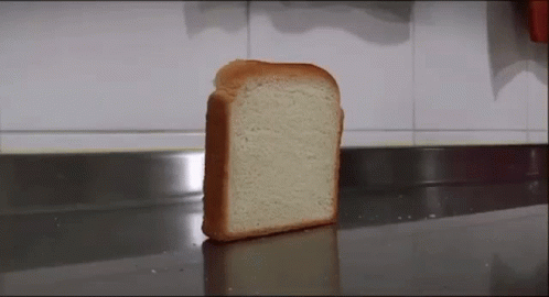 A slice of white bread standing upright on a kitchen countertop.