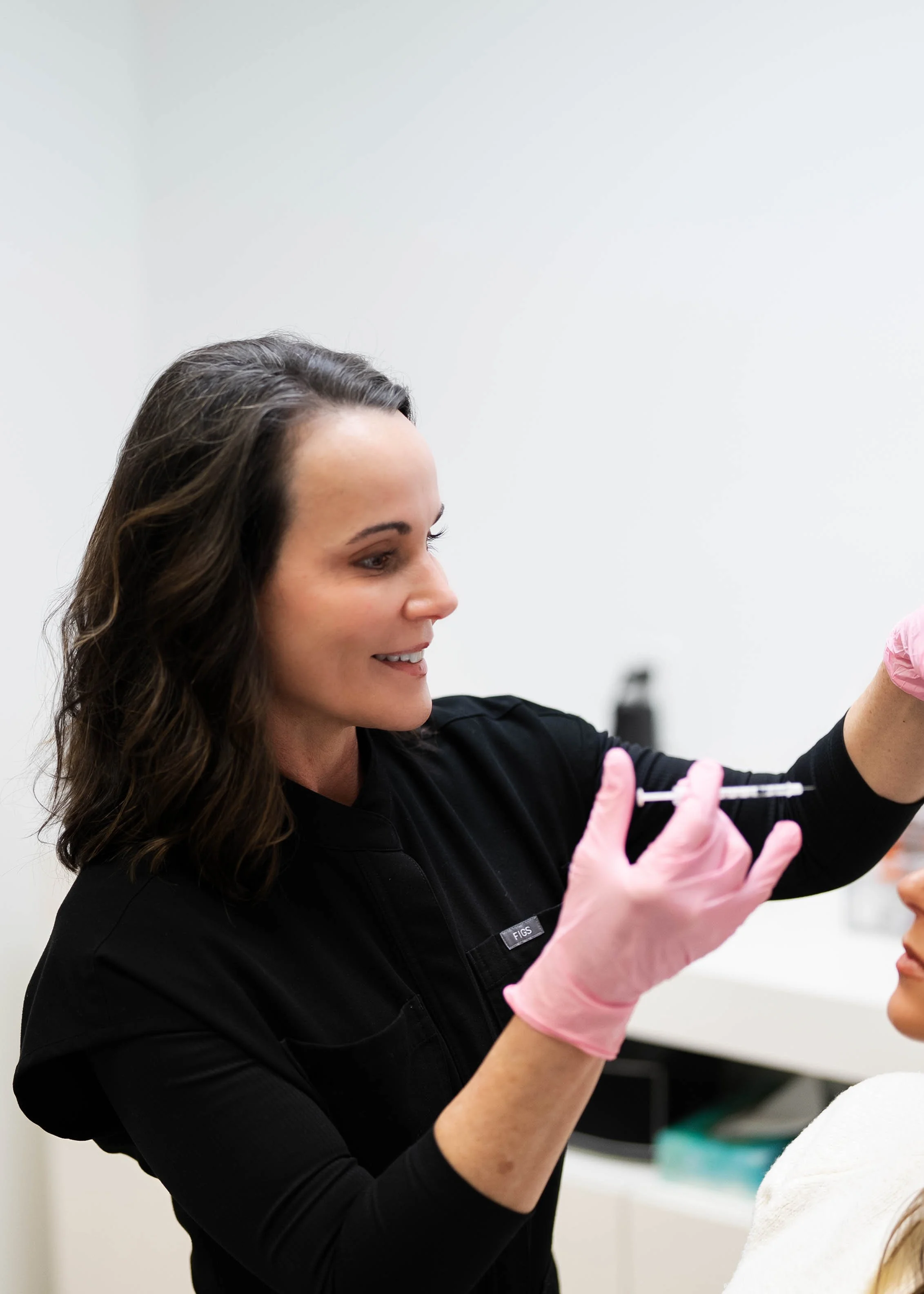 Medical professional preparing a patient with a vaccine or injection, woman wearing pink gloves, healthcare setting.