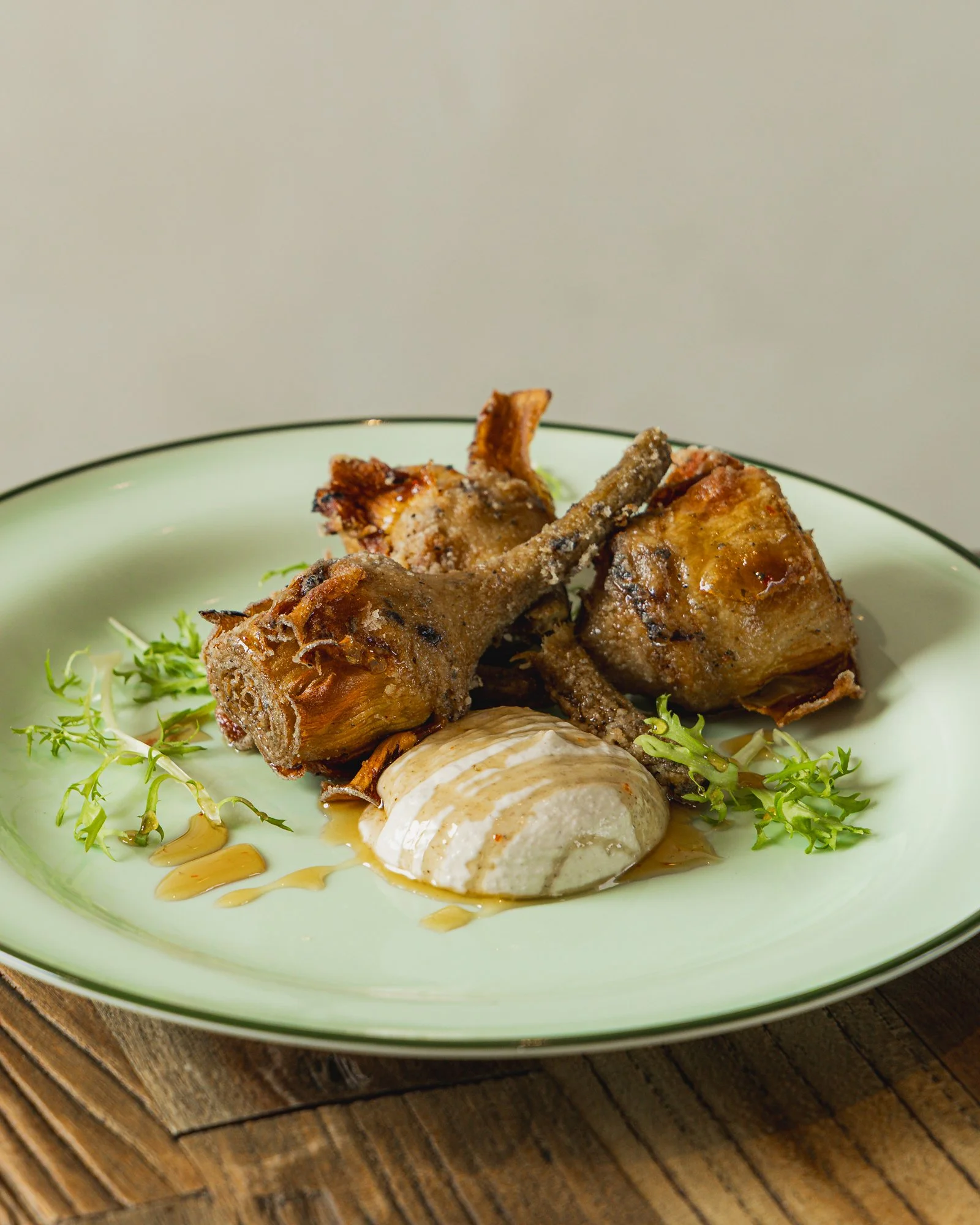 Plate with cooked lamb shanks, mashed potato, and greens garnished with gravy.