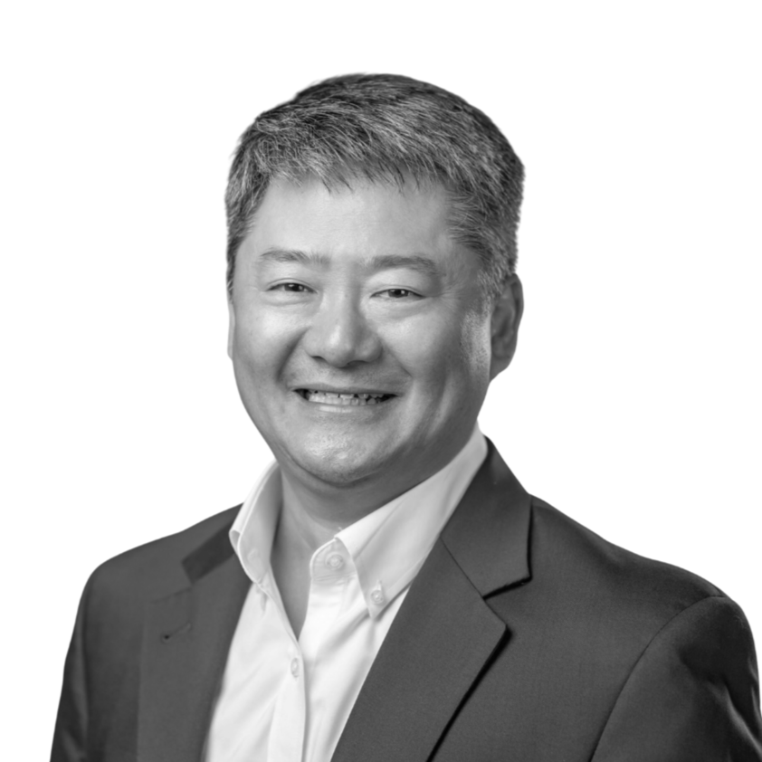 Black and white headshot of a smiling man wearing a suit jacket and collared shirt, with short hair, against a plain white background.
