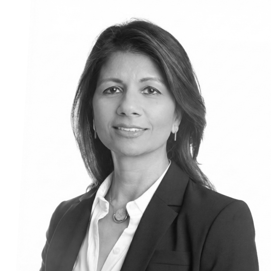 Black and white professional headshot of a woman in business attire, with shoulder-length hair, wearing earrings, a white blouse, and a blazer.